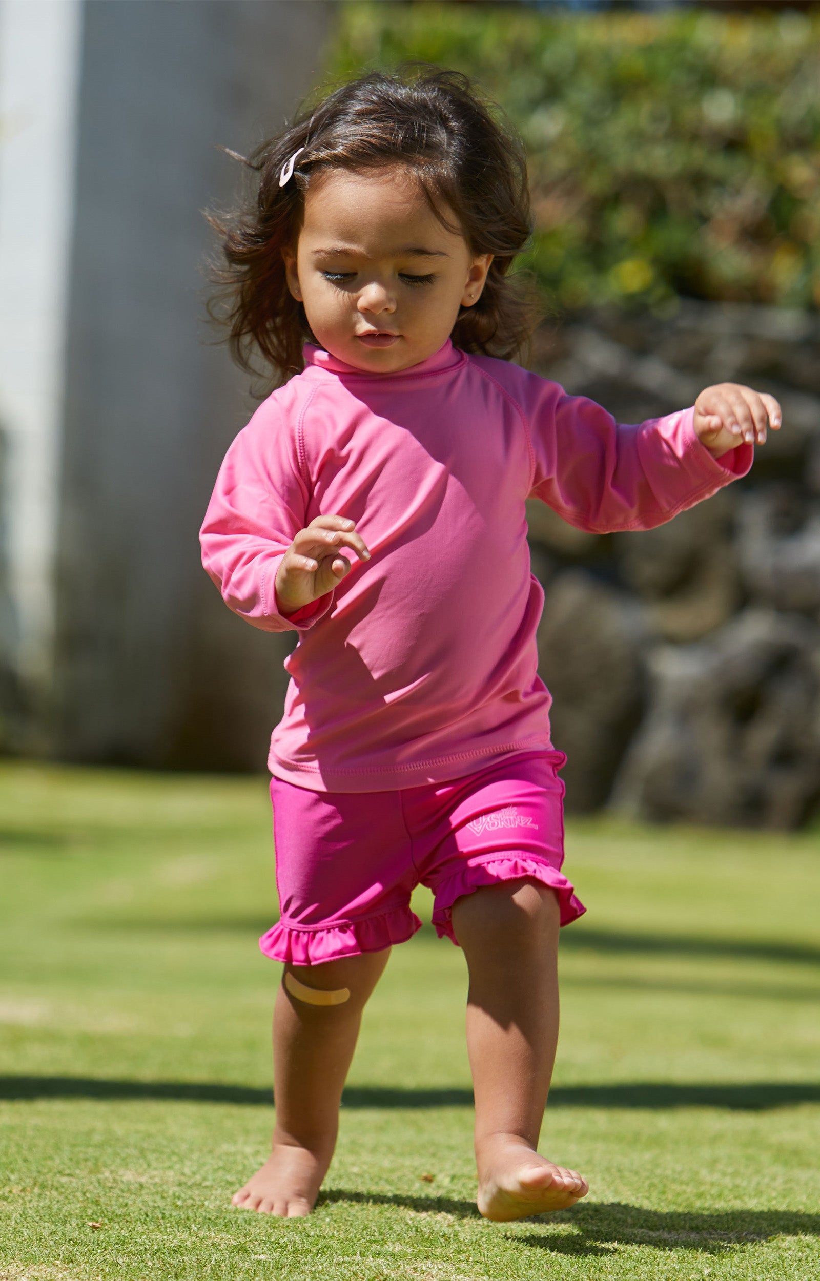 Baby girl playing in UV Skinz's baby long sleeve swim shirt|bubblegum