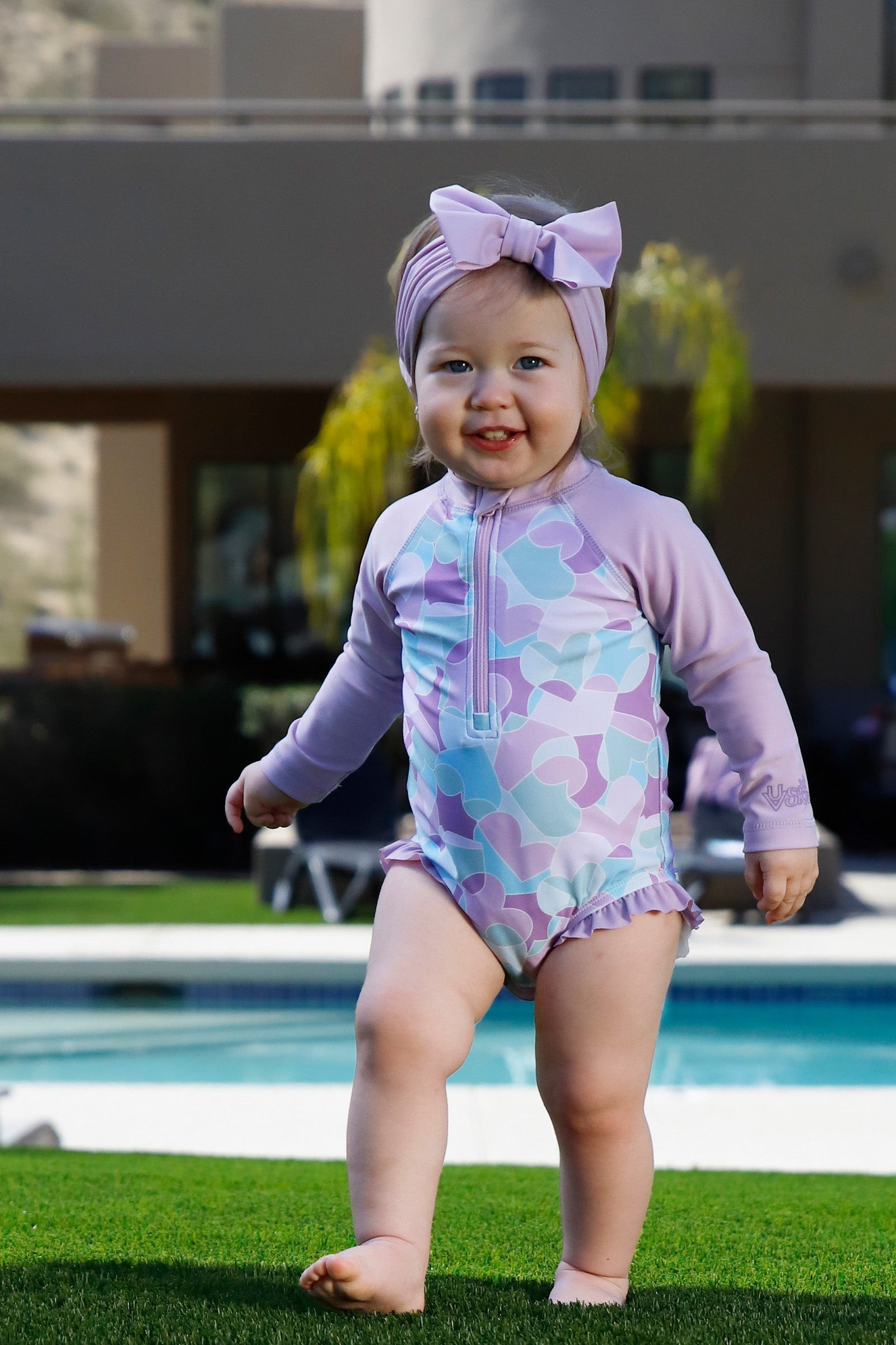 baby girl in long sleeve ruffled swim romper|puzzle-hearts