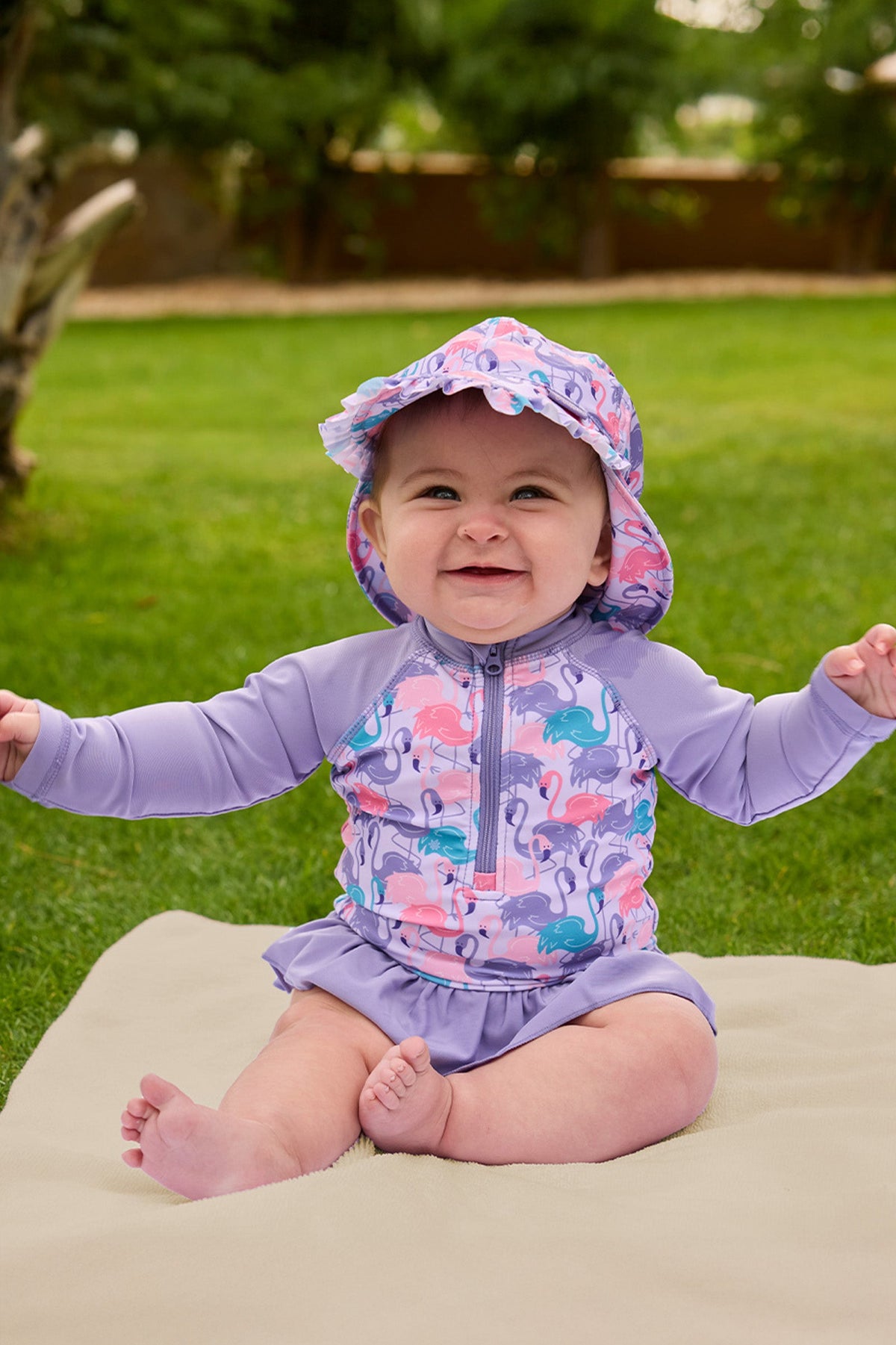 baby girl sitting in long sleeve ruffled swim suit