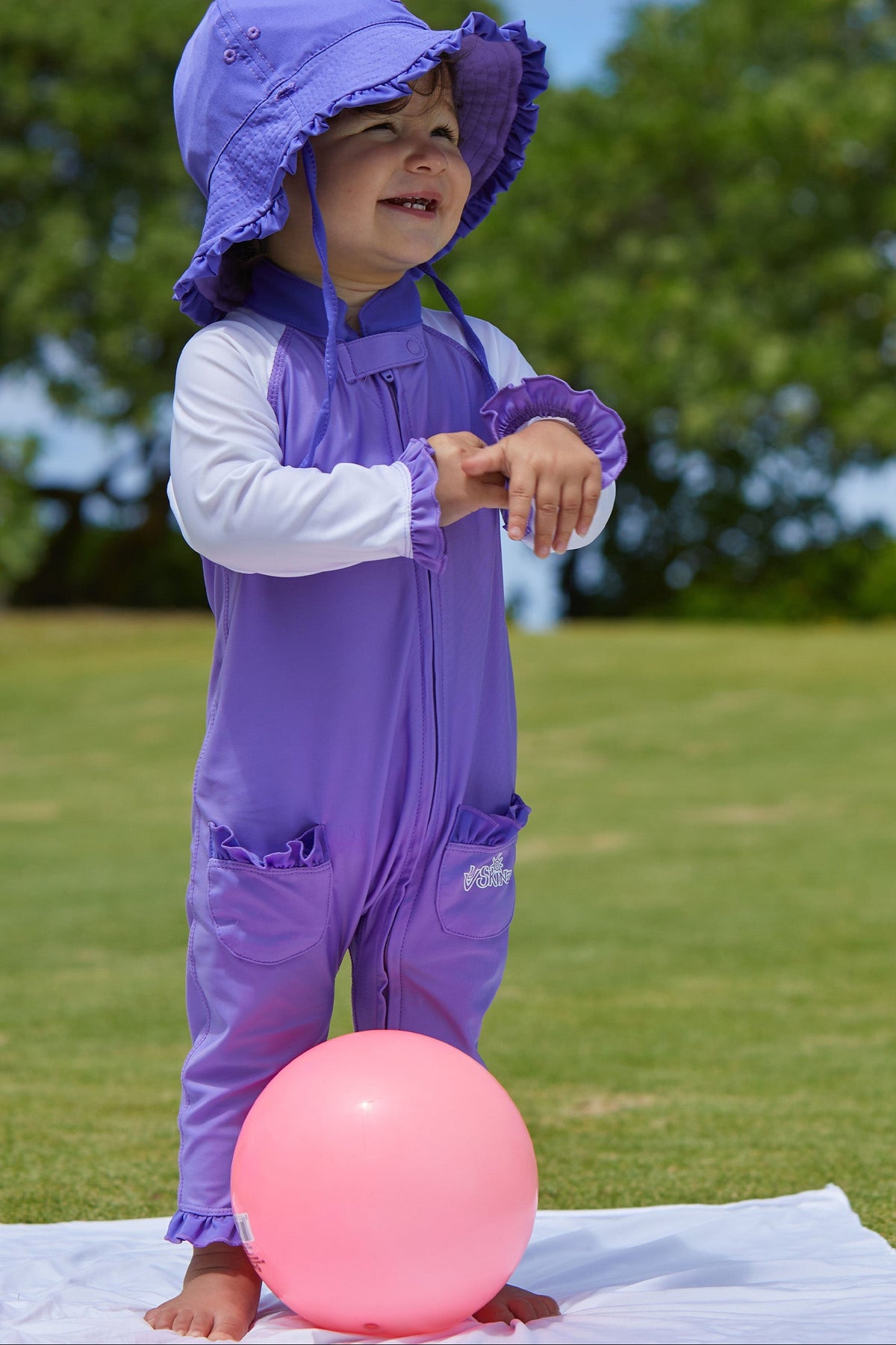 little baby girl in UV Skinz's baby girls long-sleeve swimsuit in misty purple white