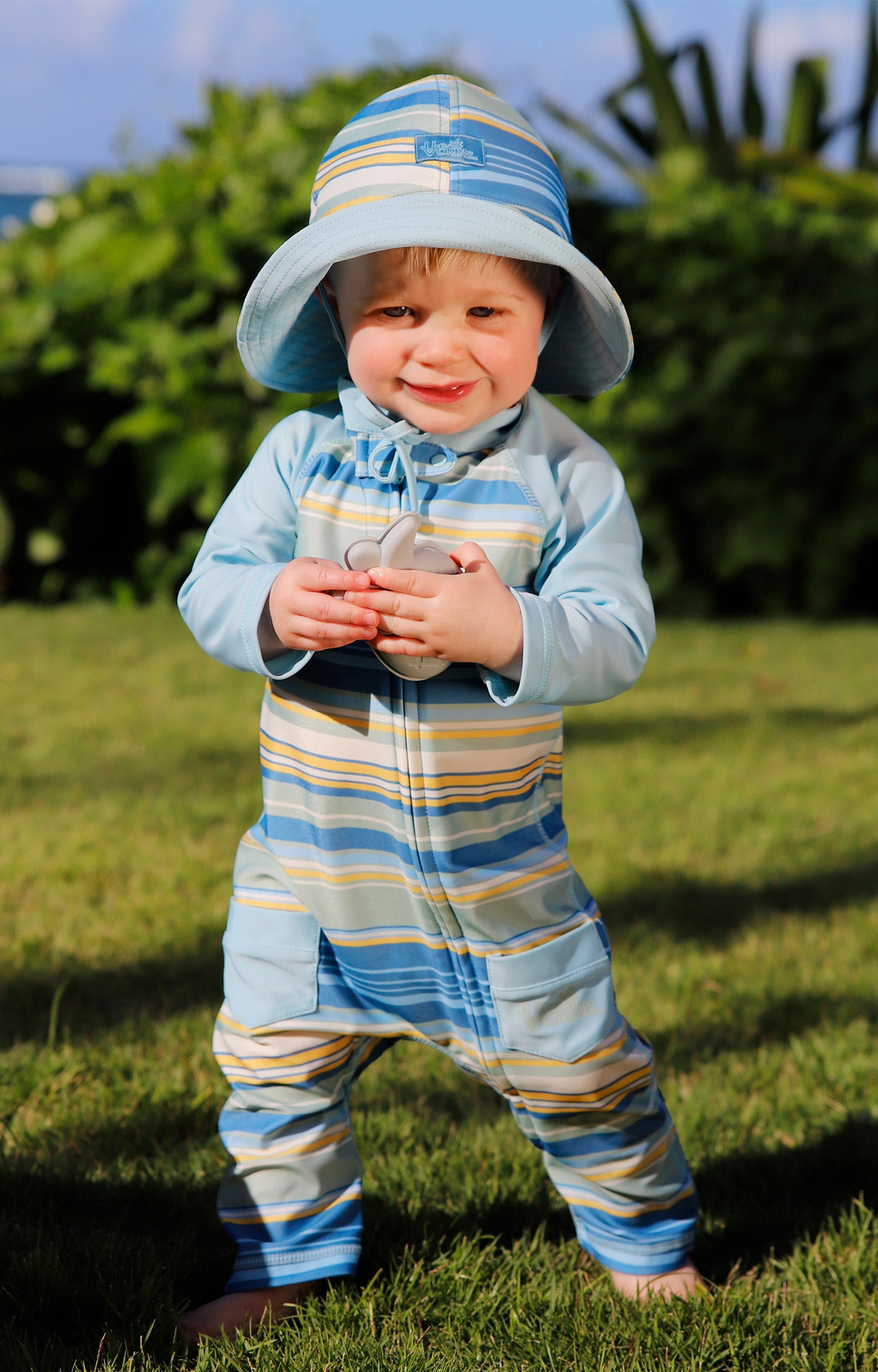 baby boy in grass in baby sun & swim suit in pinecrest stripe|pinecrest-stripe