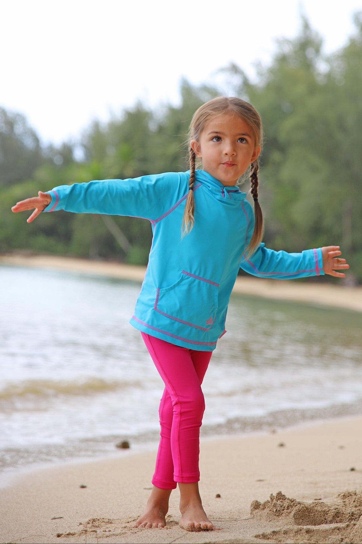 Little girl on the beach in UV Skinz's hot pink swim tights|hot-pink