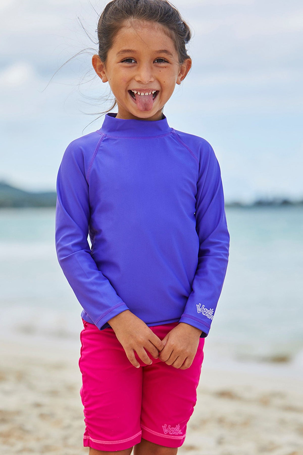 Little girl on the beach in UV Skinz's hot pink swim shorts|hot-pink