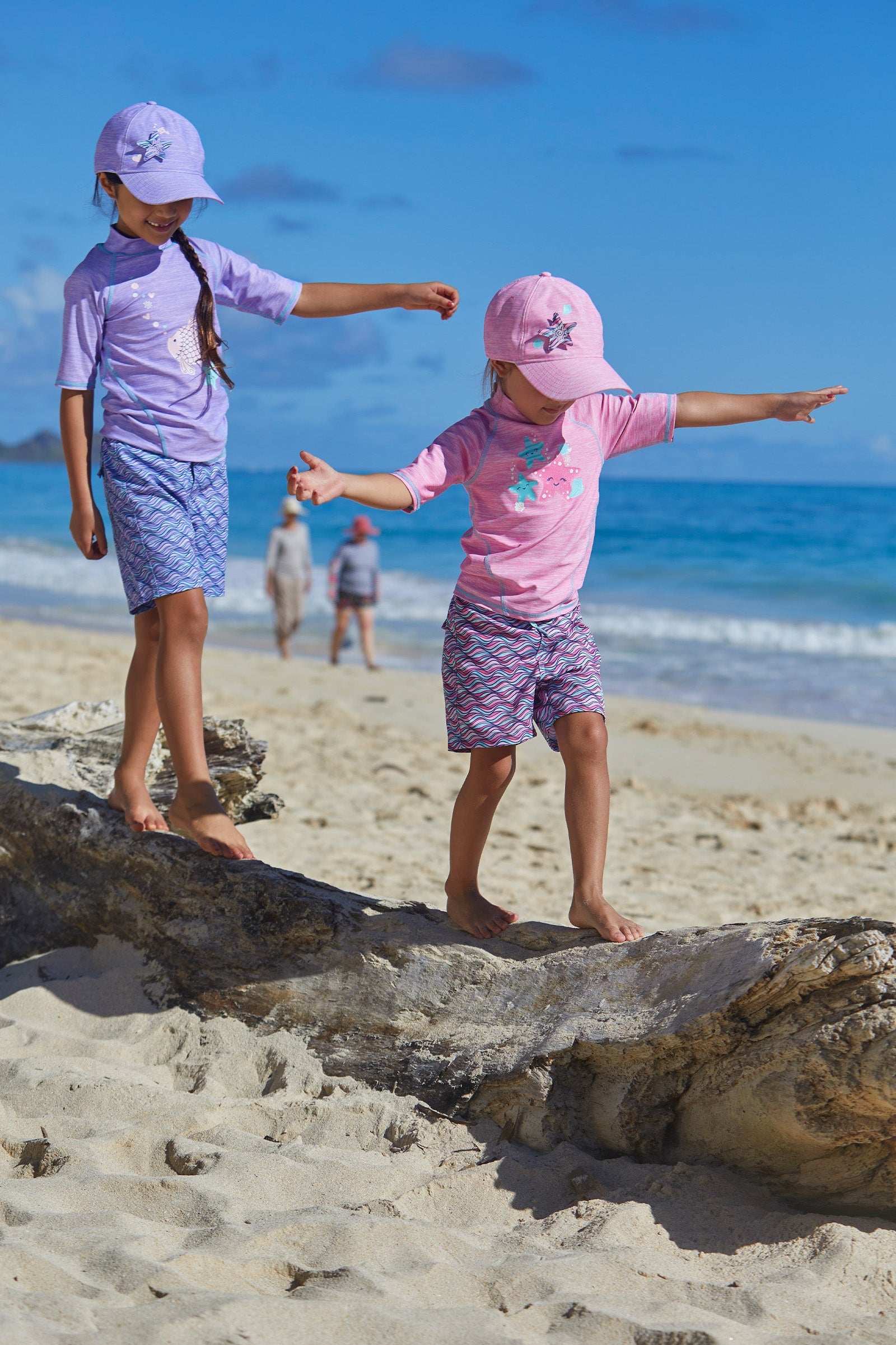 Little girls wearing UV Skinz's girl's board shorts in lilac waves|lilac-waves