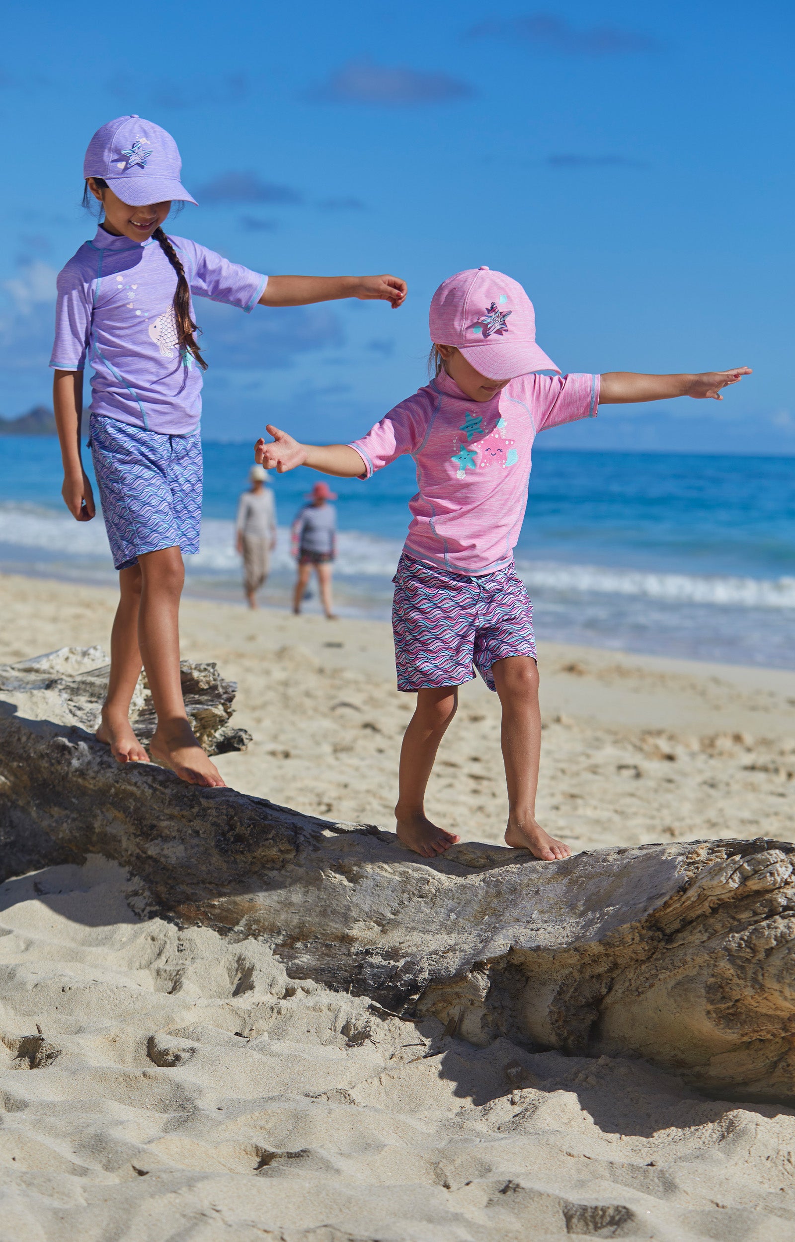 Little girls wearing UV Skinz's girl's board shorts in lilac waves|lilac-waves