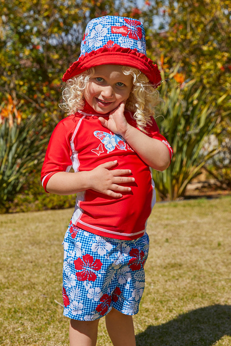 Little girl in UV Skinz's girl's board shorts|red-americana-gingham