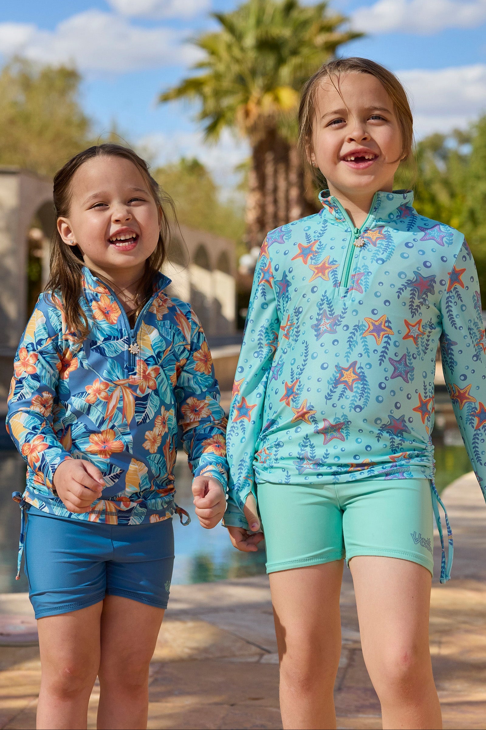 girls laughing by pool in reversible active swim shorts|maui-hibiscus-baltic