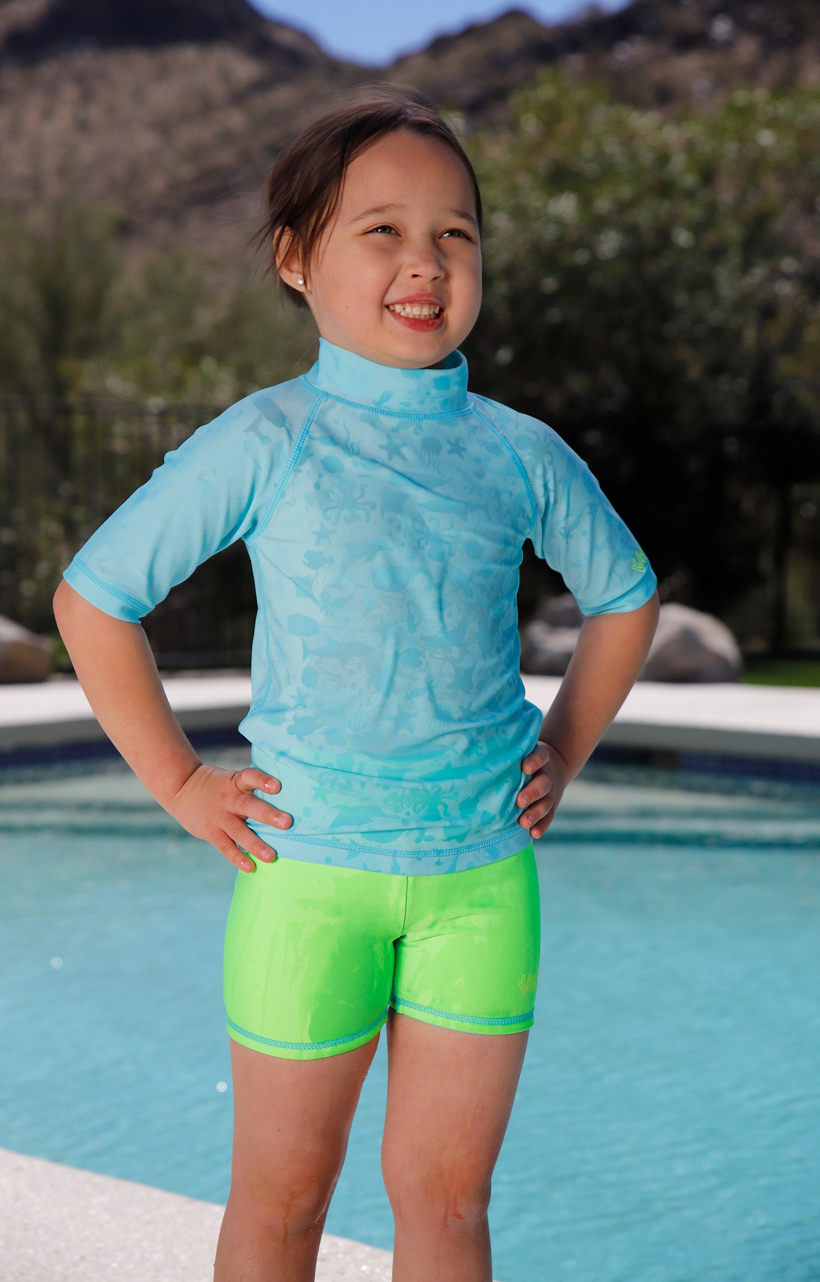 girl by pool wearing girls neon reversible active swim shorts in neon green|neon-sky-neon-green