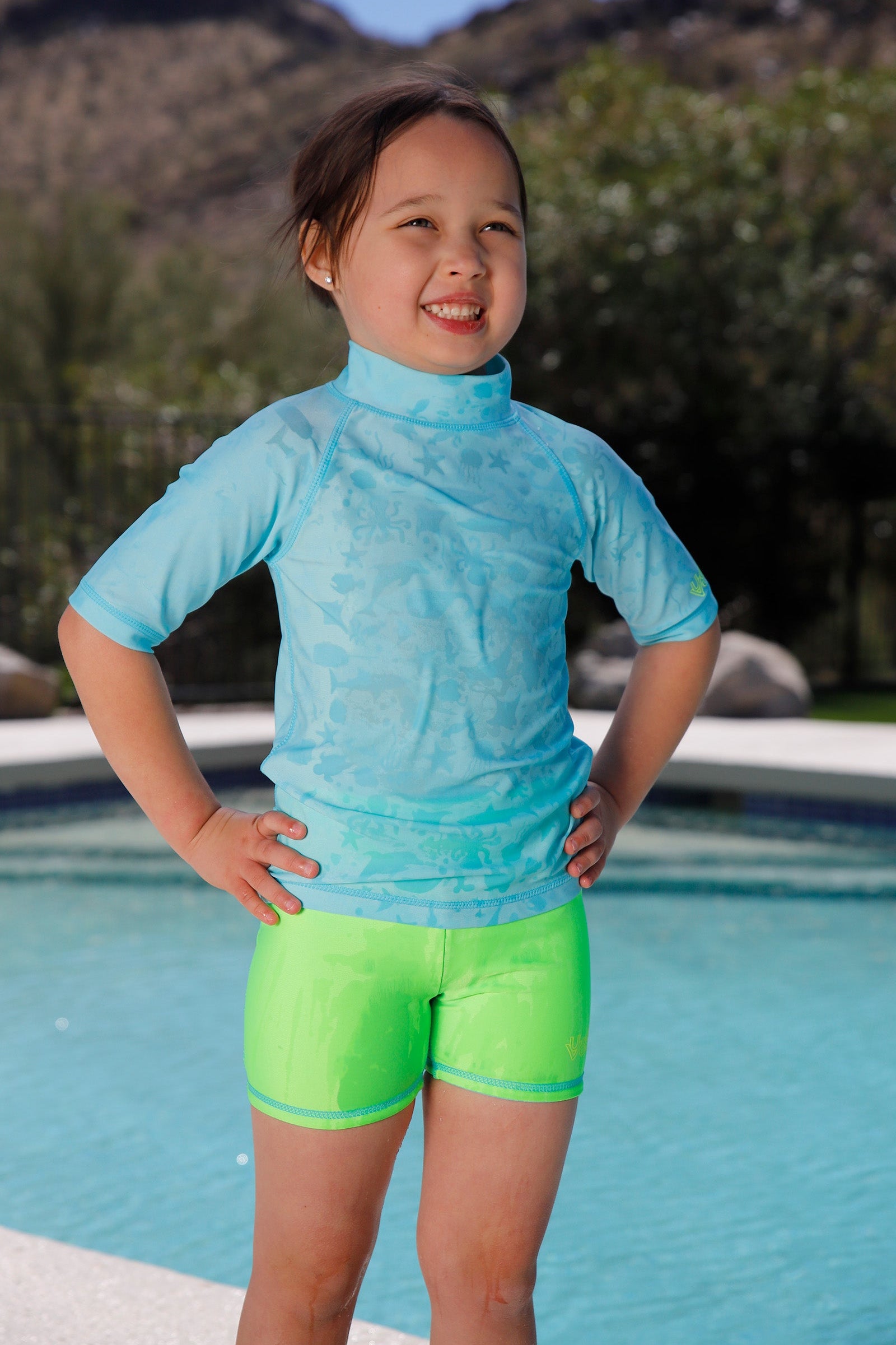 girl by pool wearing girls neon reversible active swim shorts in neon green|neon-sky-neon-green