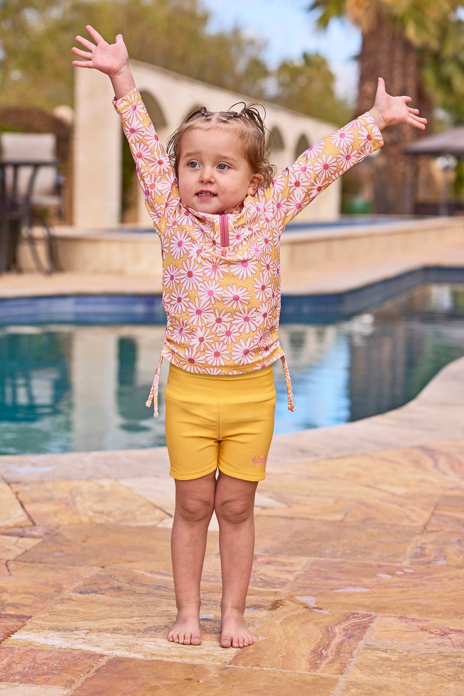 girl with arms up by pool in reversible active swim shorts|sunshine-daisies-marigold
