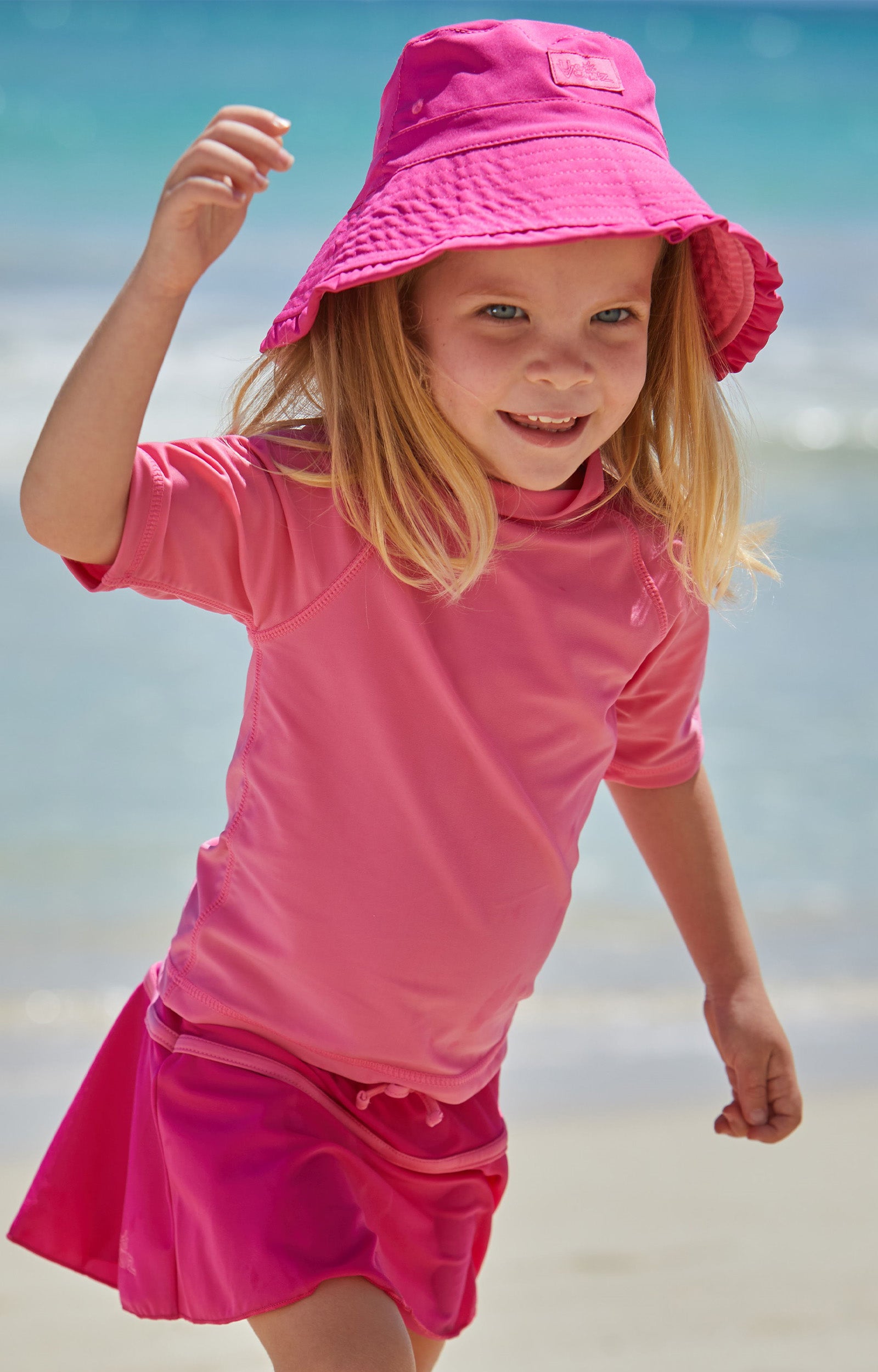 Young girl in UV Skinz's kid's short sleeve swim shirt in bubblegum|bubblegum