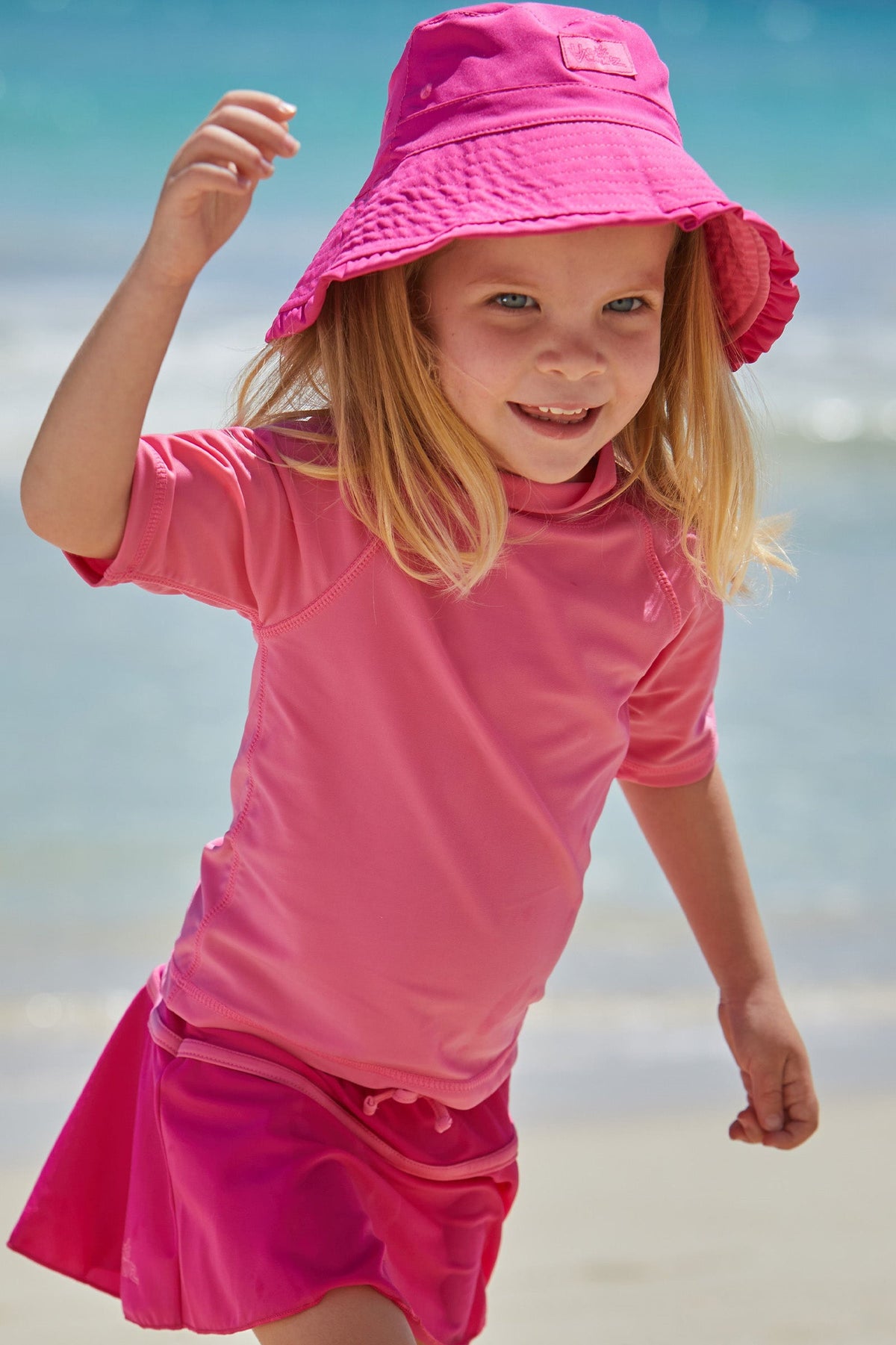 Young girl in UV Skinz's kid's short sleeve swim shirt in bubblegum|bubblegum