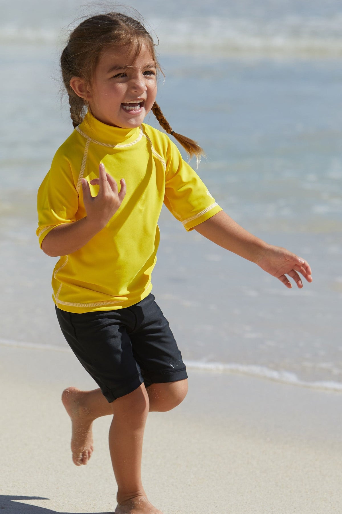Little girl in UV Skinz's kid's short sleeve swim shirt in cyber yellow|cyber-yellow