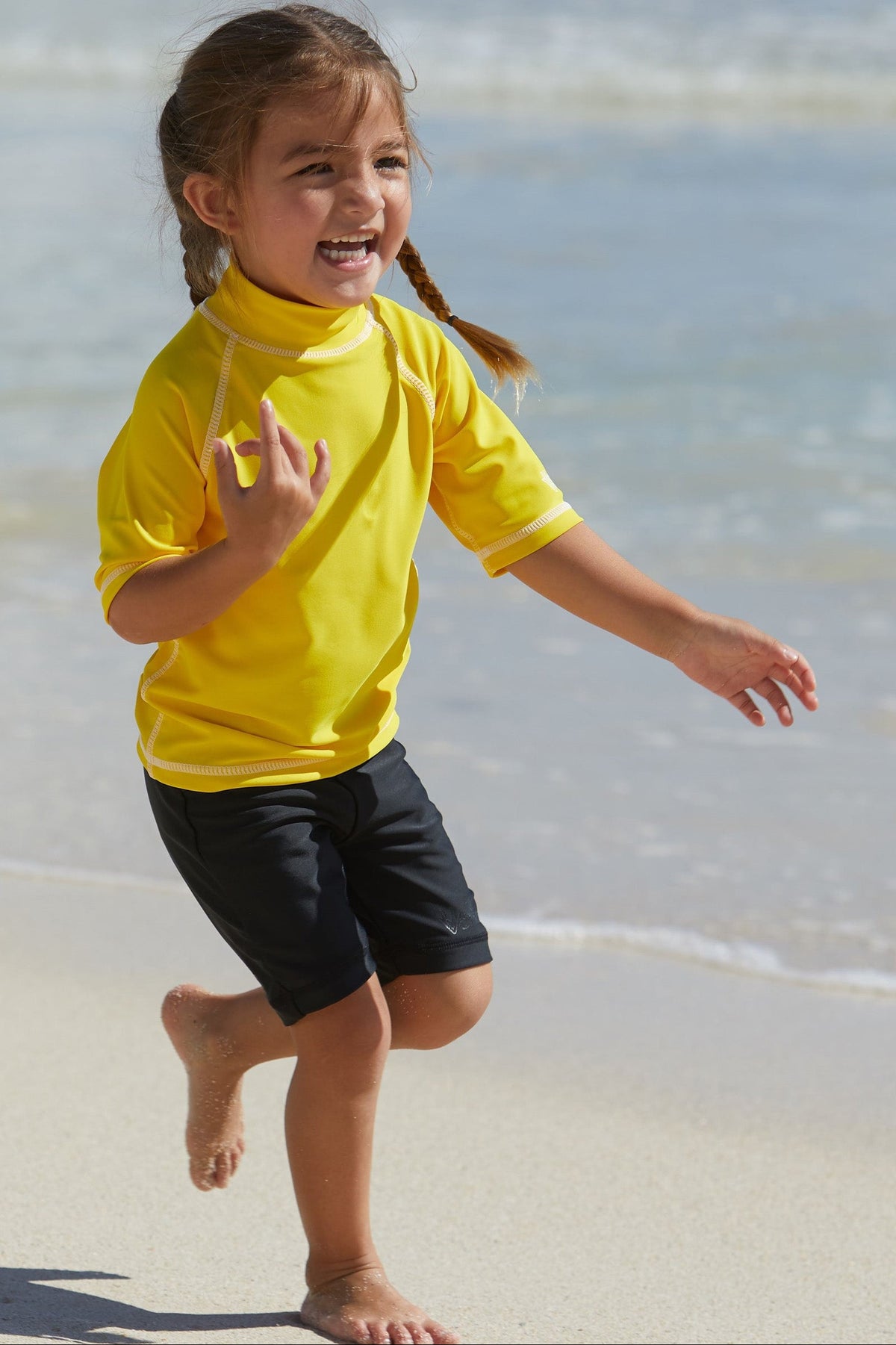 Little girl playing in UV Skinz's black swim shorts|black