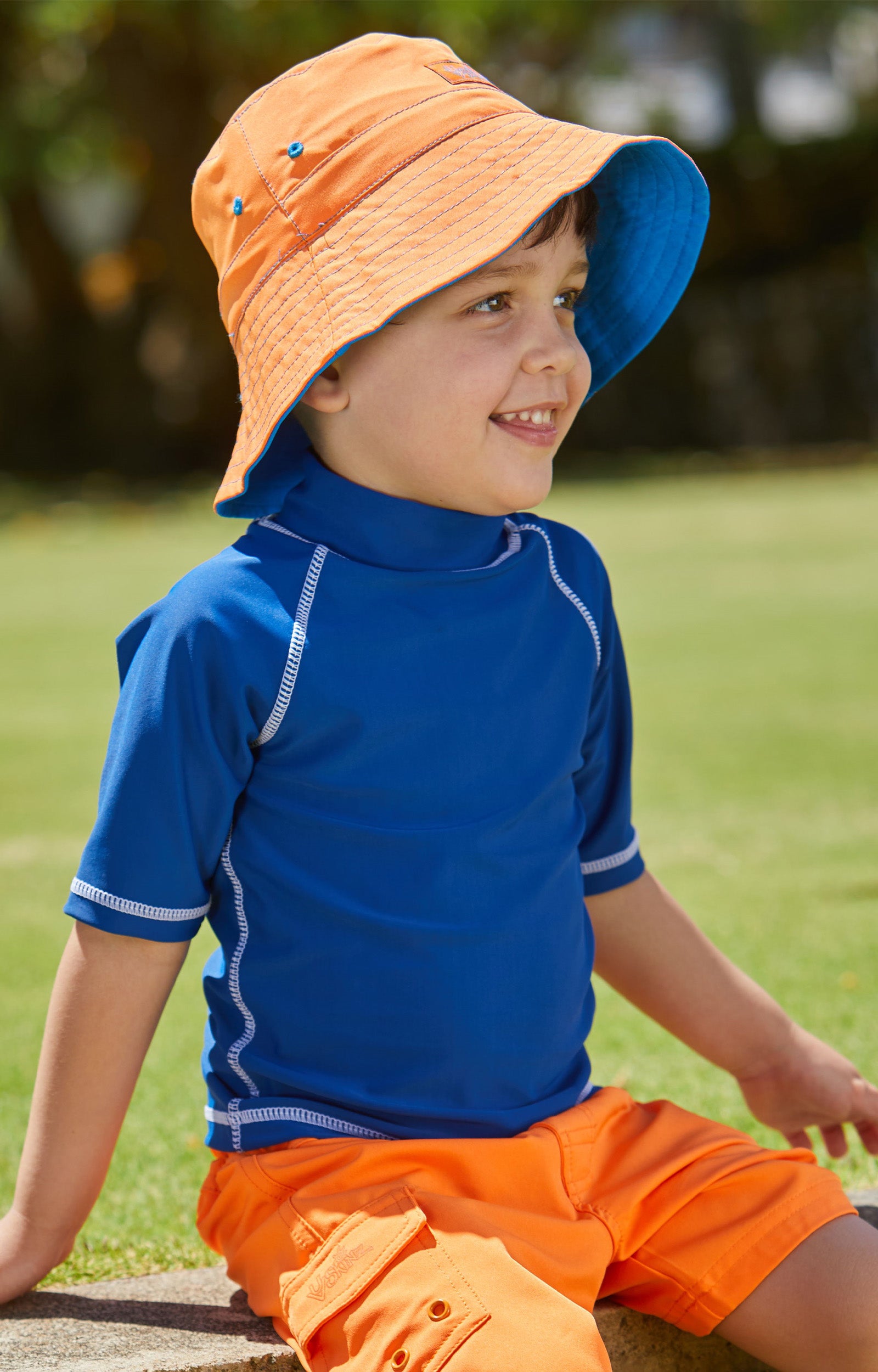 Young boy in UV Skinz's kid's short sleeve swim shirt in navy|navy