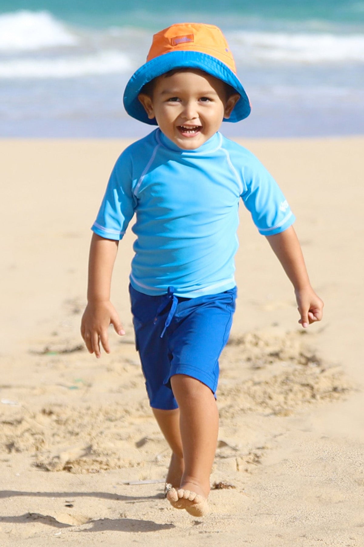 Little boy on the beach in kid's short sleeve swim shirt in ocean blue|ocean-blue