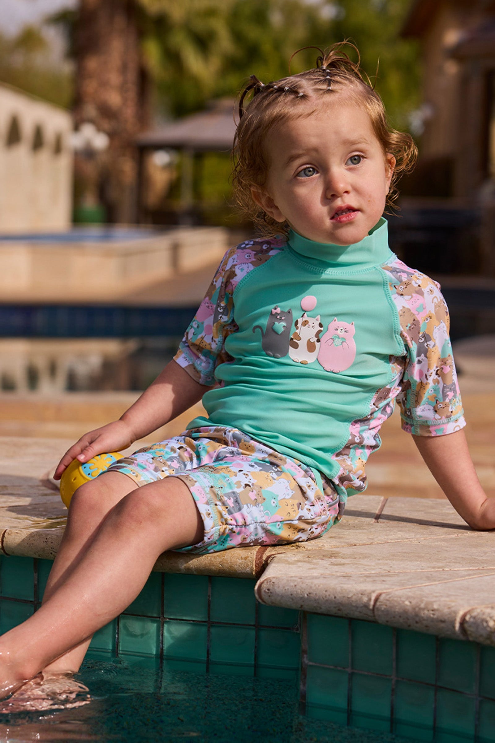 girl in short sleeve sunny swim shirt with feet in the pool|jumping-for-joy