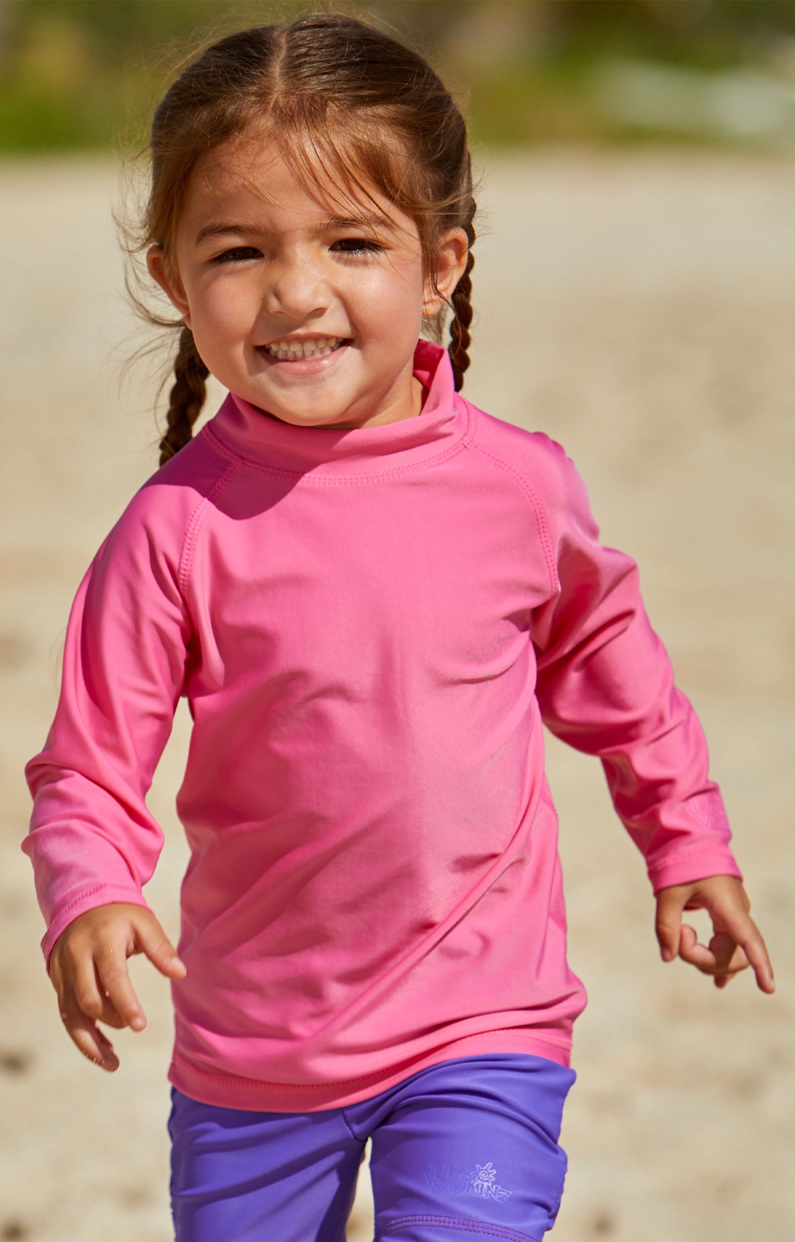 Little girl playin on the beach in the kid's long sleeve swim shirt in bubblegum|bubblegum