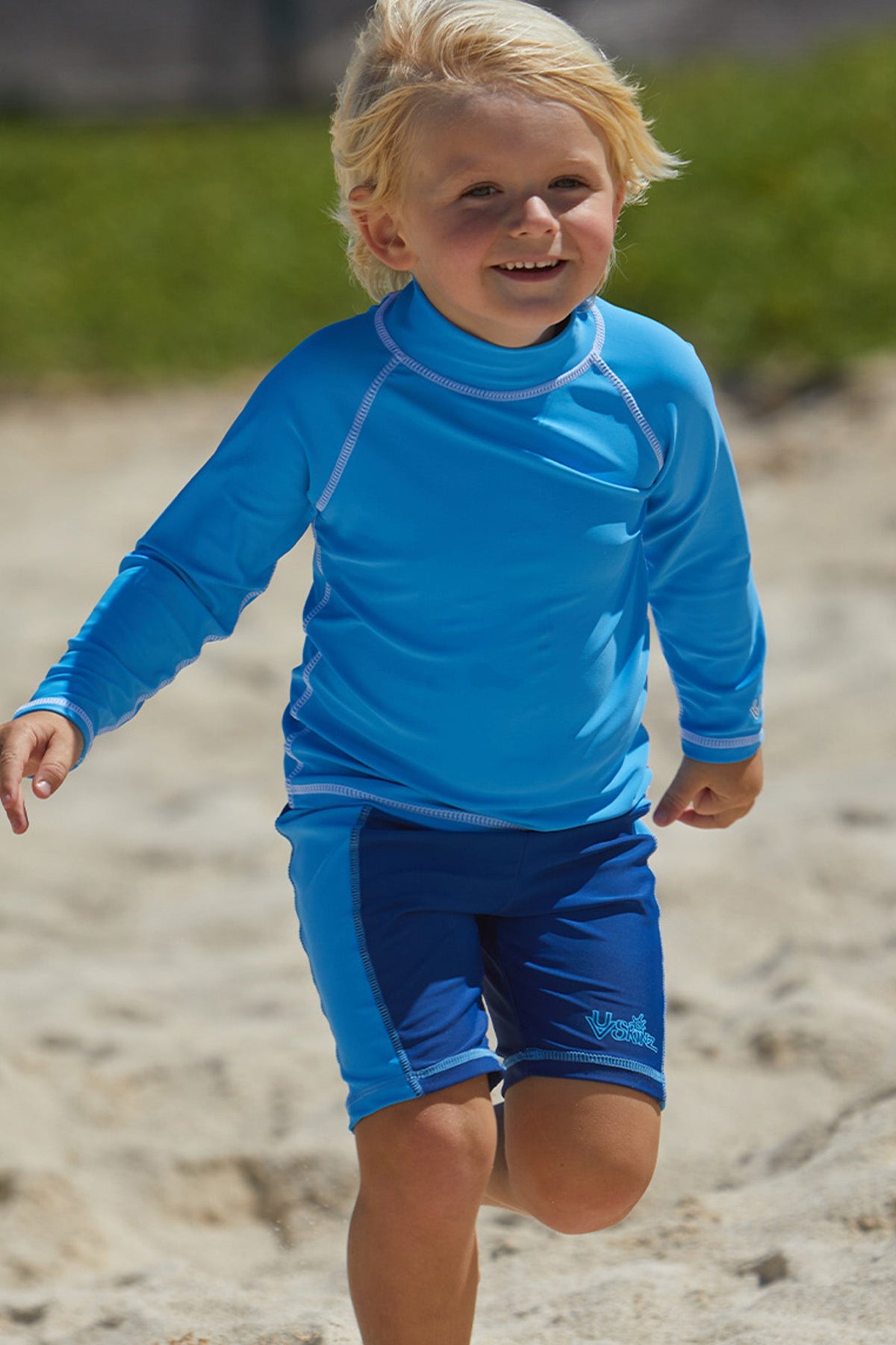 Little boy playin in the sand in UV Skinz's kid's long sleeve swim shirt in ocean blue|ocean-blue