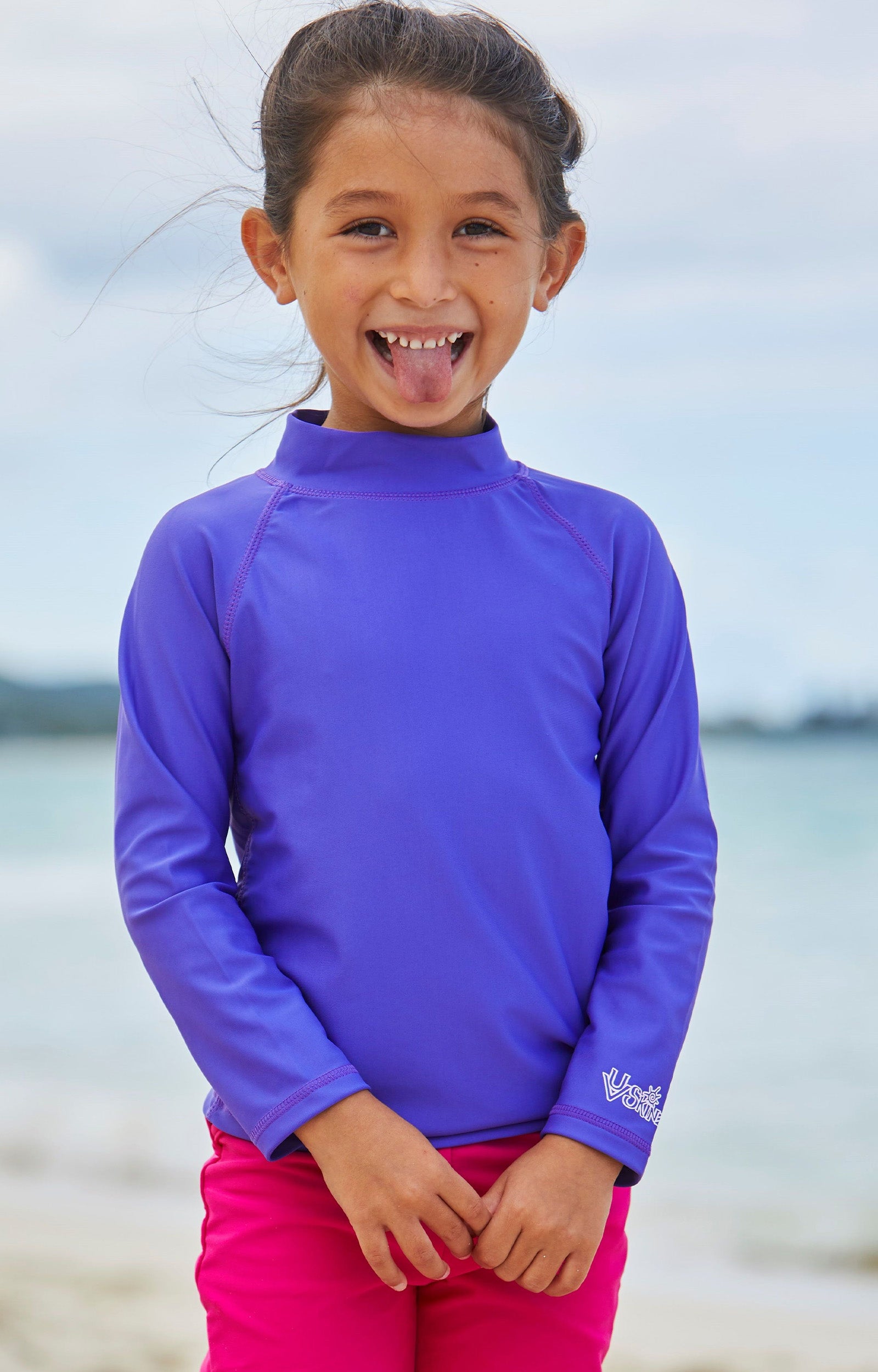 Girl playing on the beach in UV Skinz's kid's long sleeve swim shirt in purple|purple