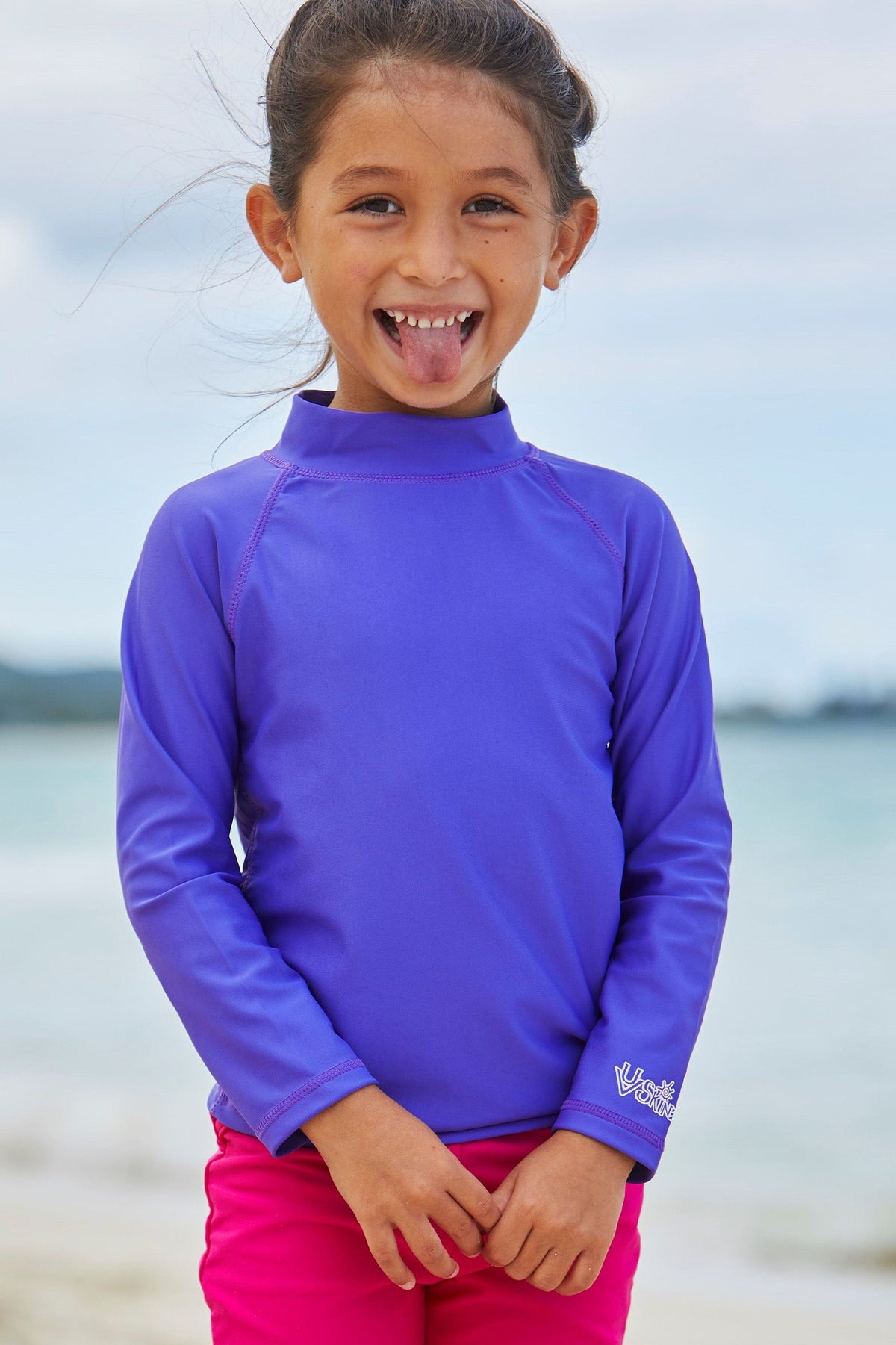 Girl playing on the beach in UV Skinz's kid's long sleeve swim shirt in purple|purple