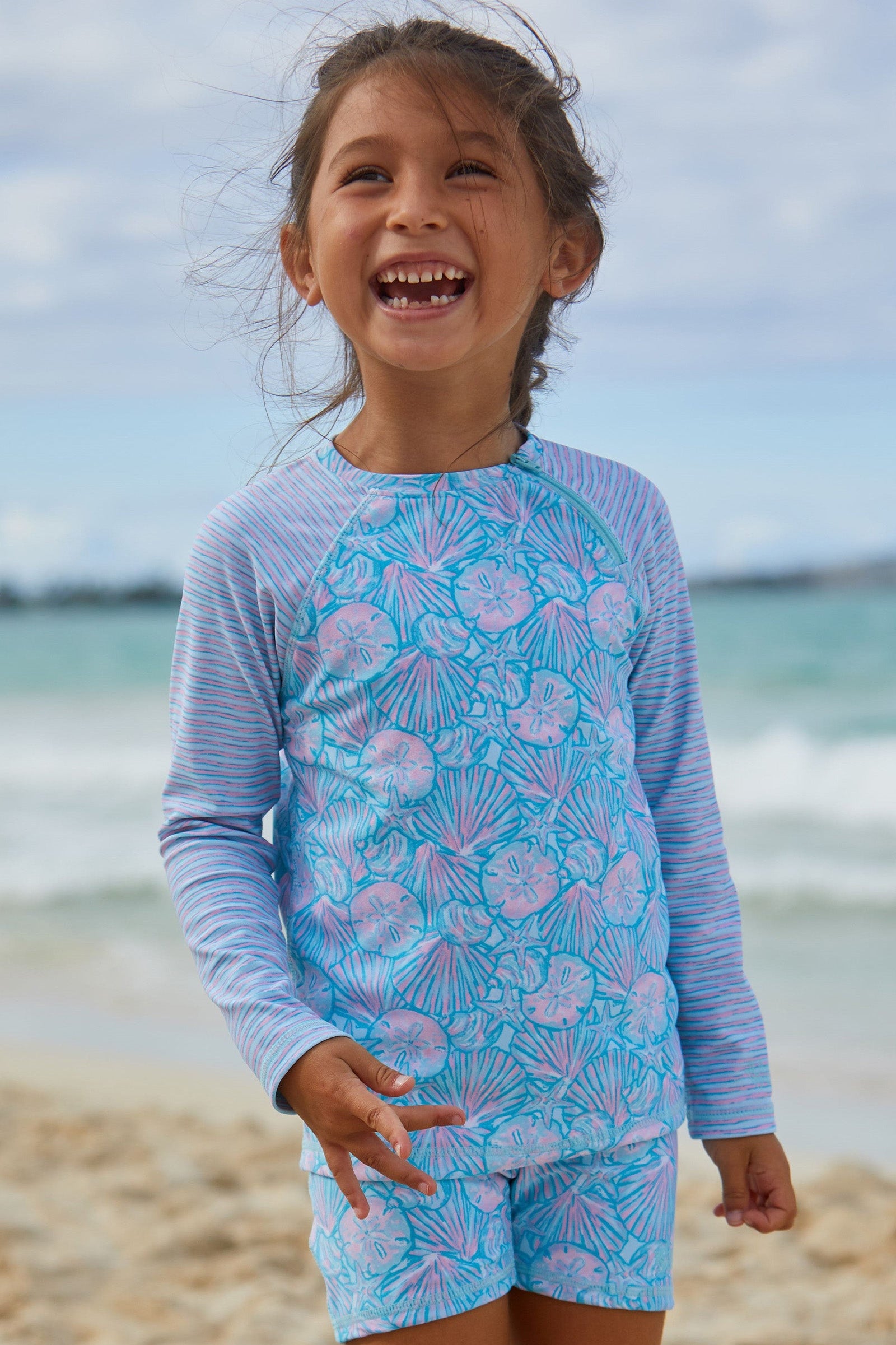 Girl in UV Skinz's girls long sleeve rash guard in candy shell stripes|candy-shells-stripes