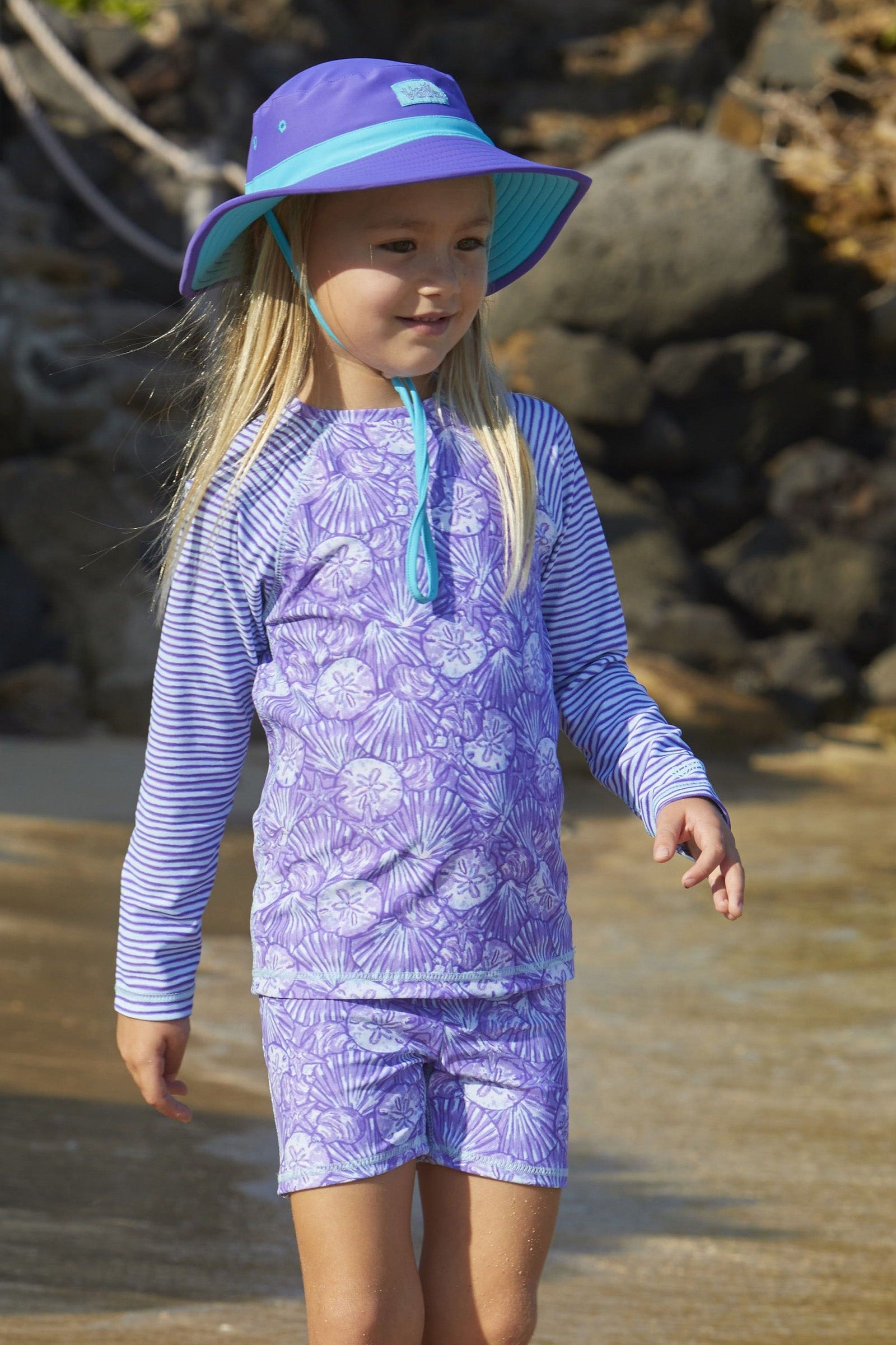 Little girl in UV Skinz's girls long sleeve rash guard in dreamy shells stripe|dreamy-shells-stripes