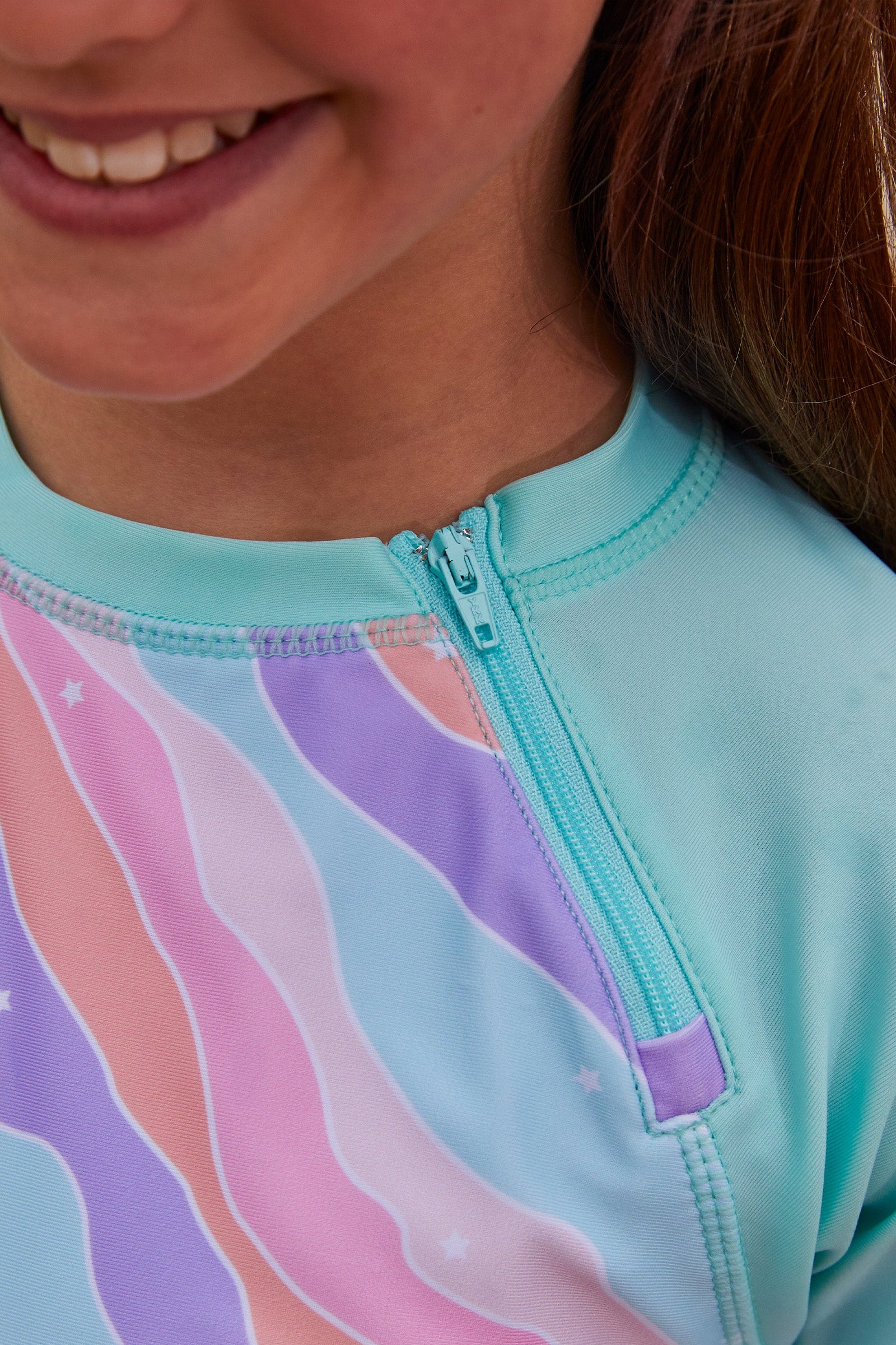 Close up of the zipper on the girl's long sleeve swim shirt in petal power|petal-power