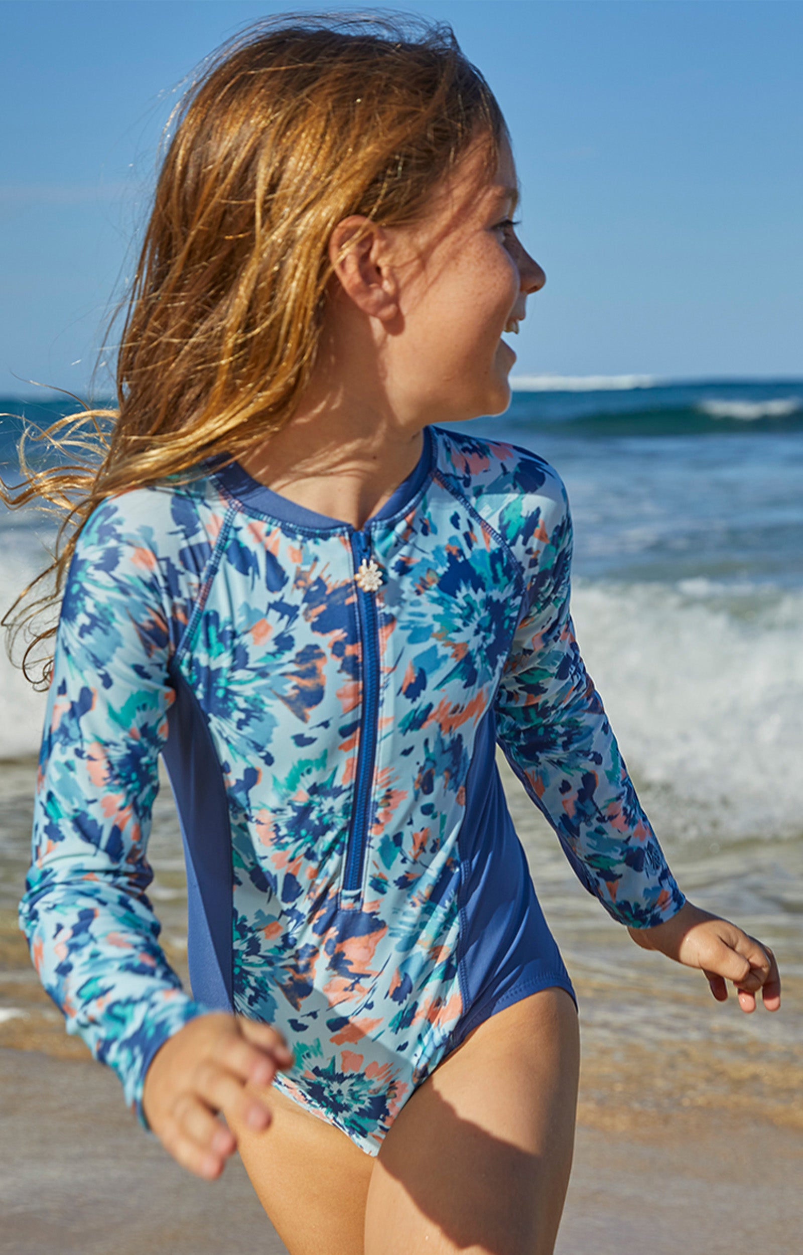 Young girl in UV Skinz's girl's long sleeve swimsuit in yosemite tie dye|yosemite-tie-dye