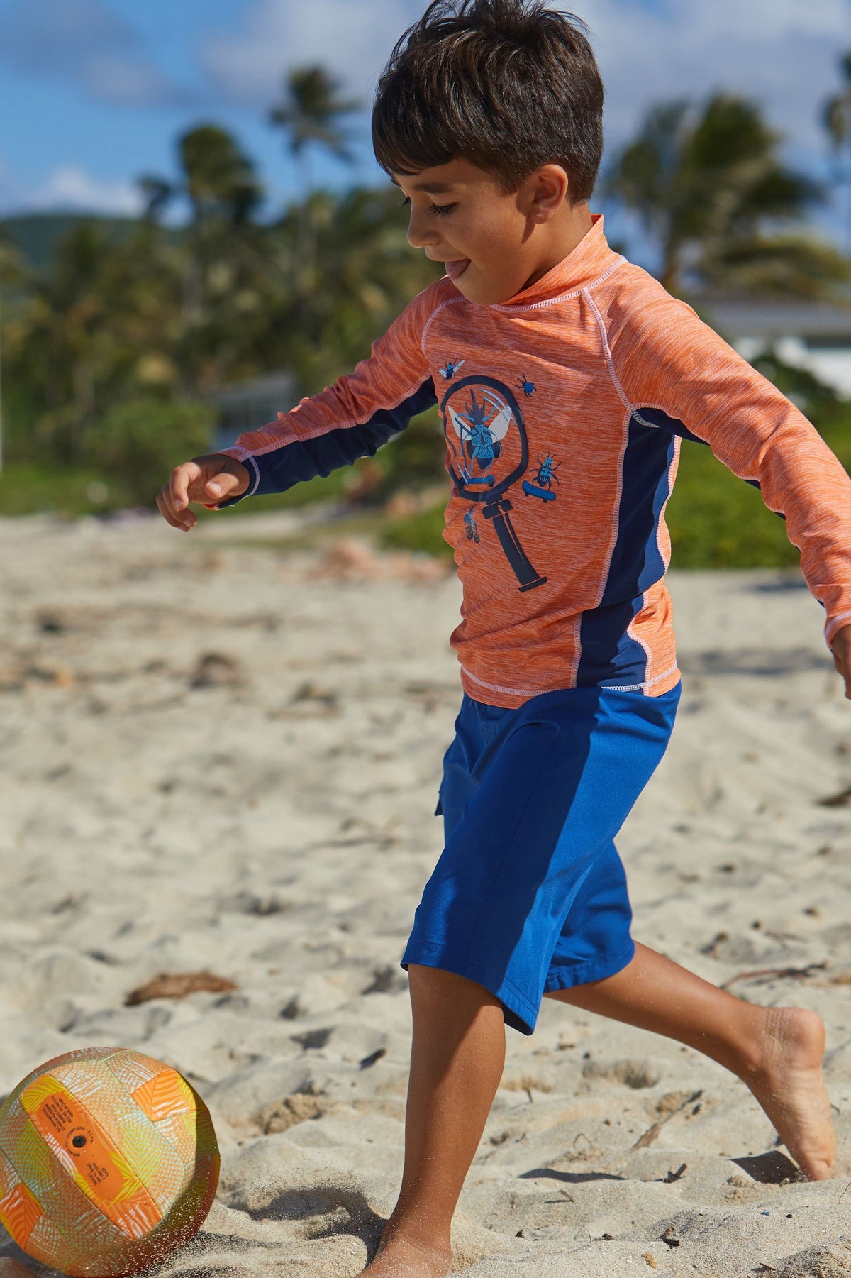 Boy Playing Soccer on the Beach in UV Skinz's Boy's Classic Board Shorts in Navy