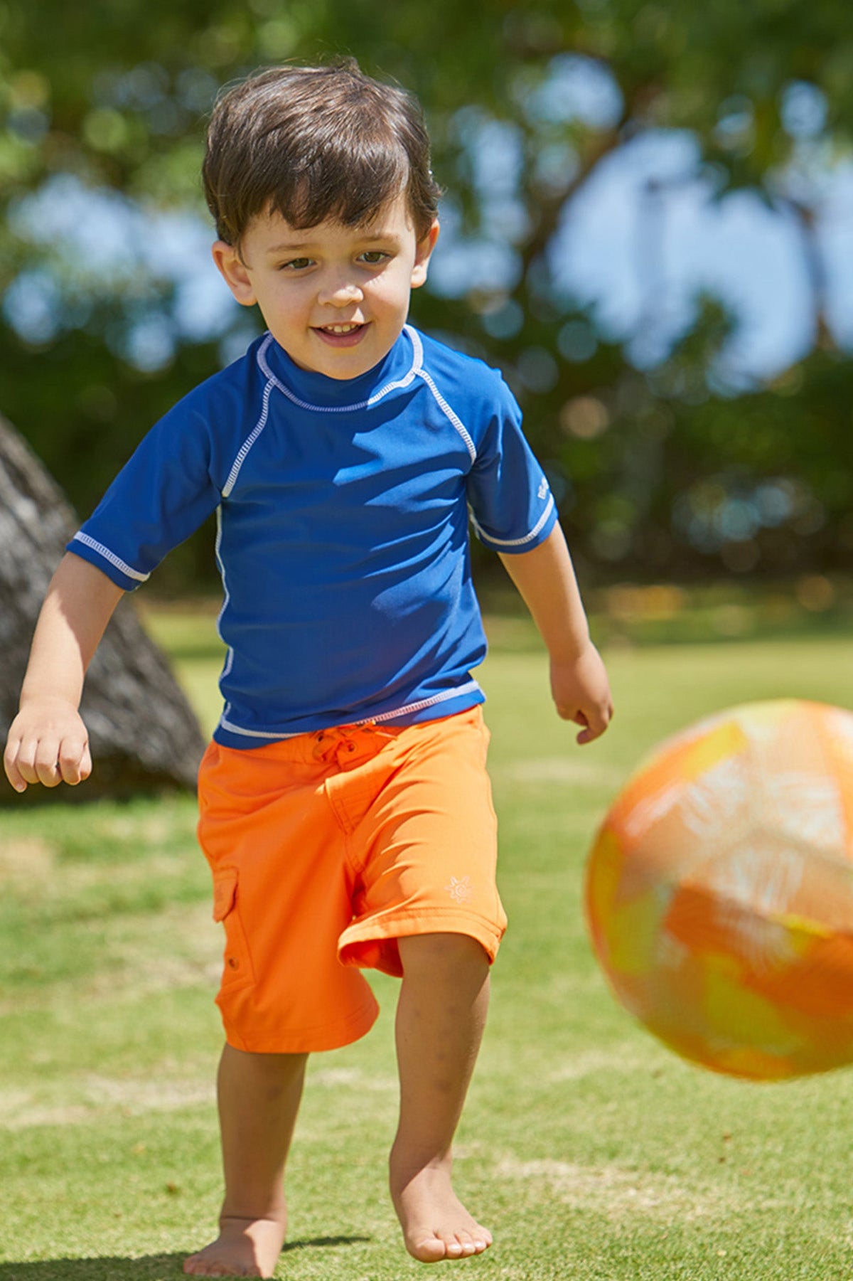 Young Boy Playing in the Sun in the Boy's Classic Board Shorts in Orange