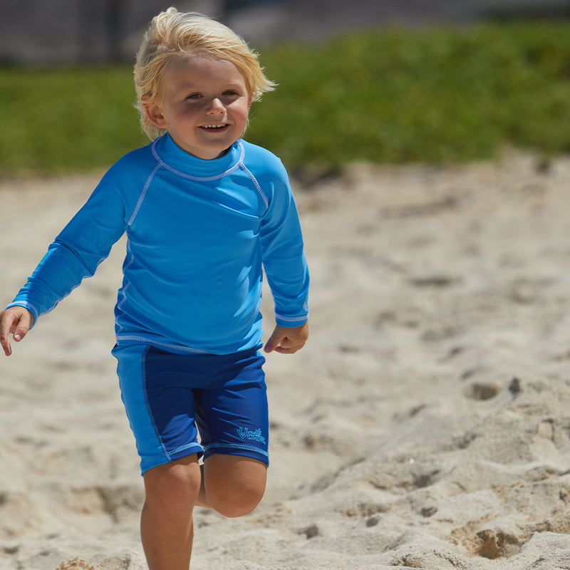 Little boy playin in the sand in UV Skinz's kid's long sleeve swim shirt in ocean blue|ocean-blue