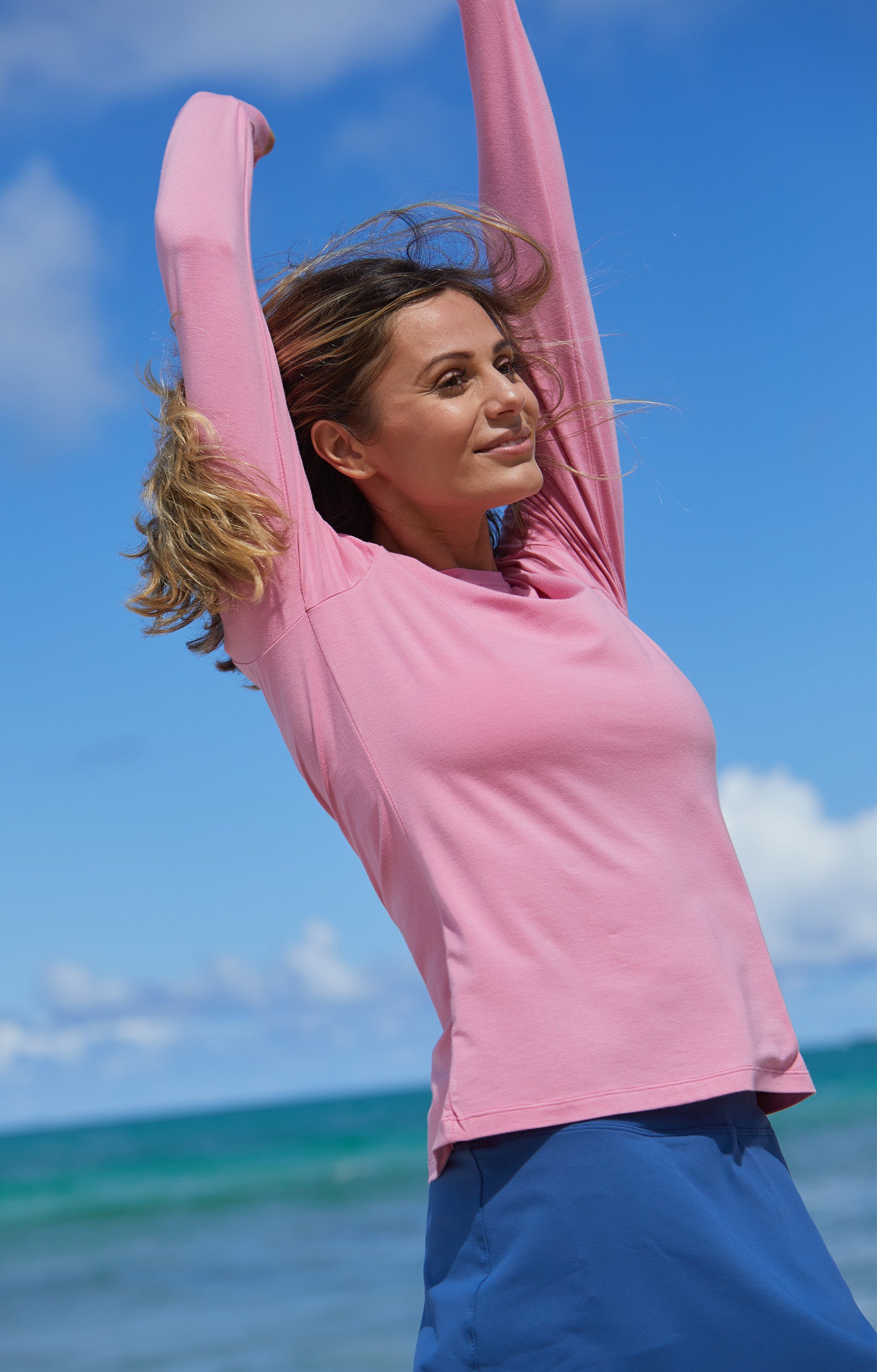 Woman Walking Down the Beach in UV Skinz's Women's Long Sleeve Everyday Tee in Wild Rose|wild-rose