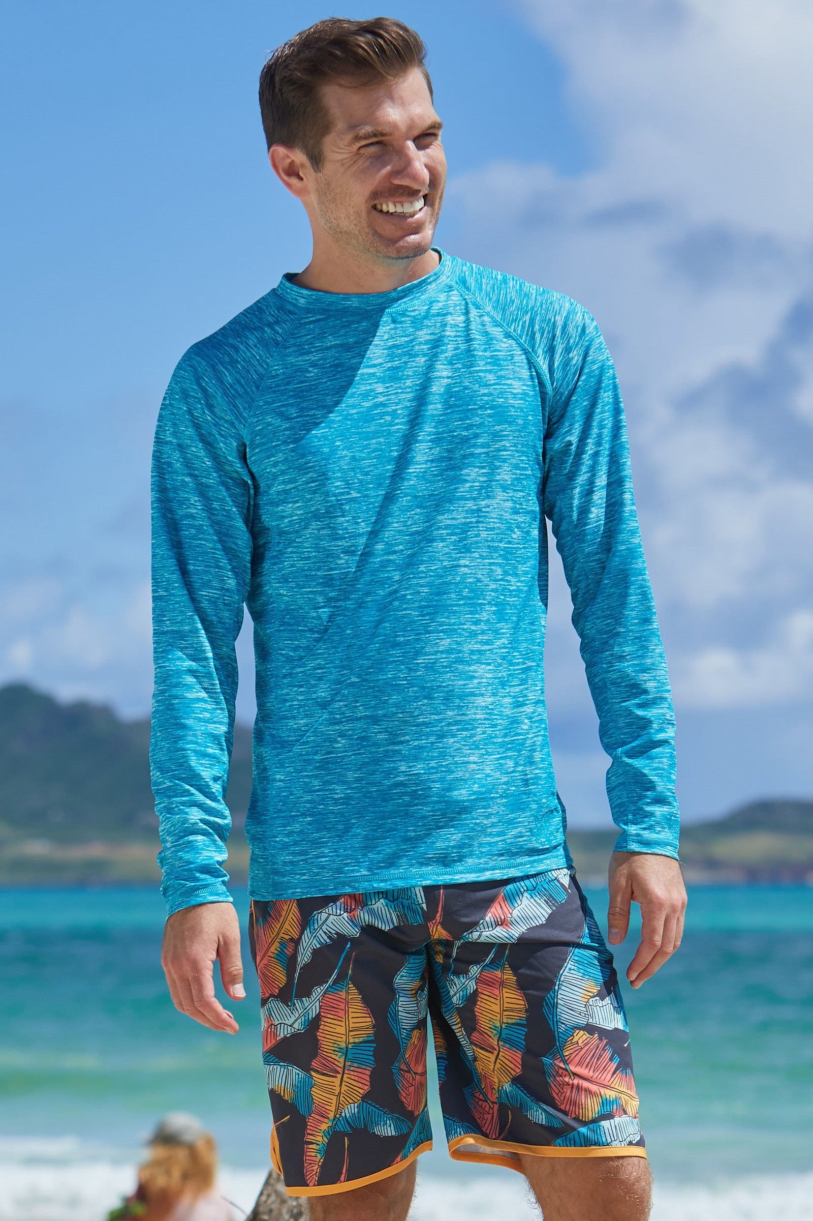 Man on the beach in UV Skinz's men's long sleeve crew swim shirt in caribbean jaspe|caribbean-jaspe