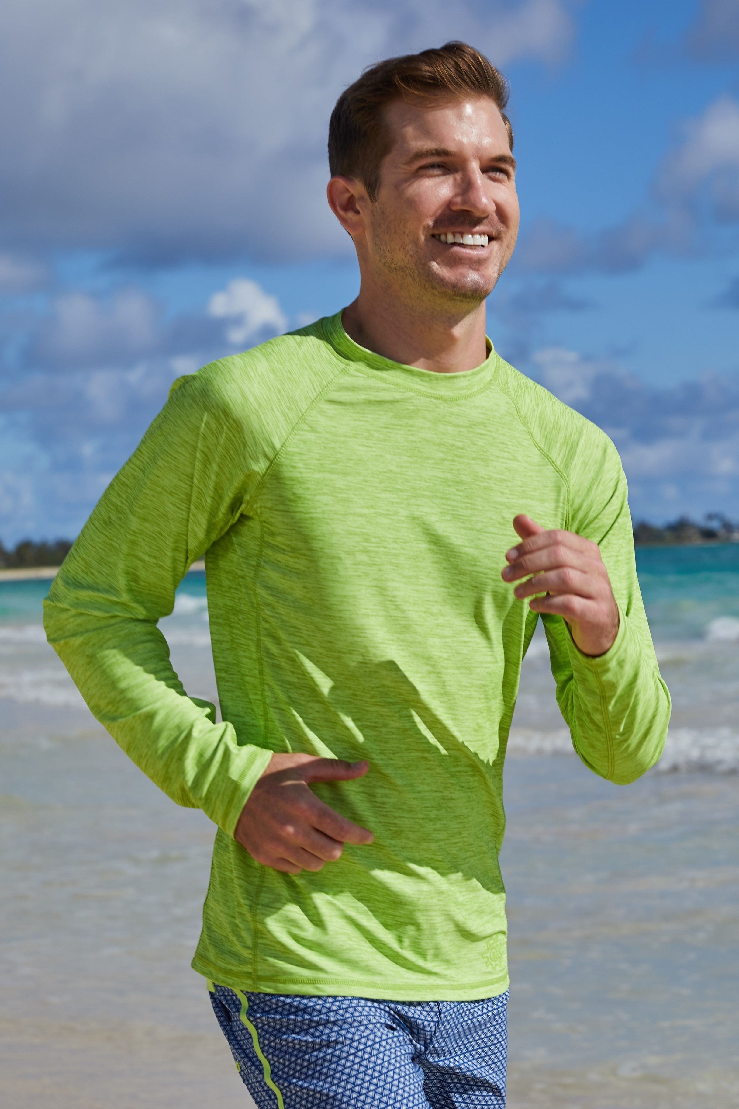 Man running on the beach in UV Skinz's men's long sleeve crew swim shirt in electric green jaspe|electric-green-jaspe
