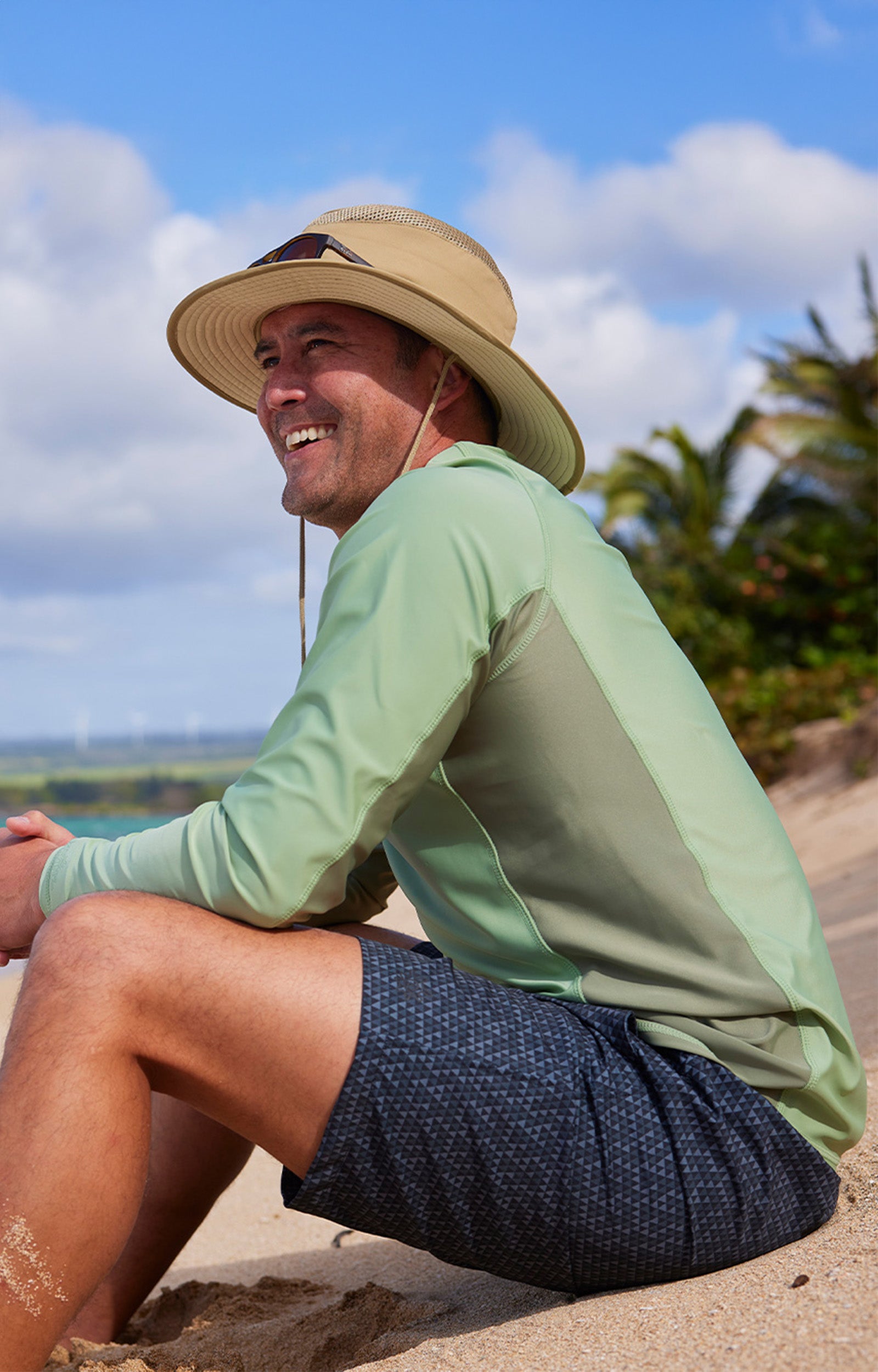 man sitting on sand on beach in men's long sleeve crew sun & swim shirt|sage-washed-olive
