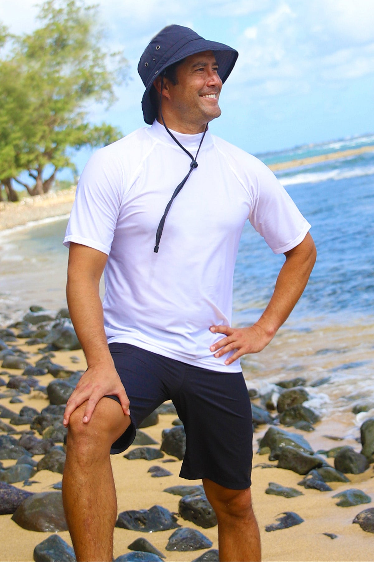 Man on the beach in UV Skinz's men's coastal board shorts in black|black