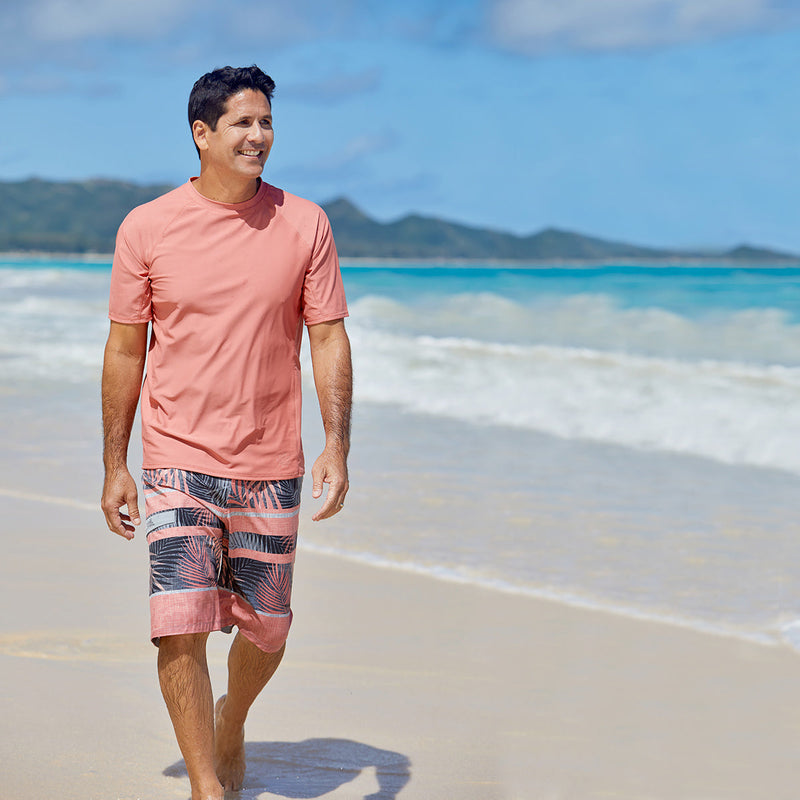Man on the beach in UV Skinz's men's coastal board shorts in canyon tropical stripe|canyon-tropical-stripe