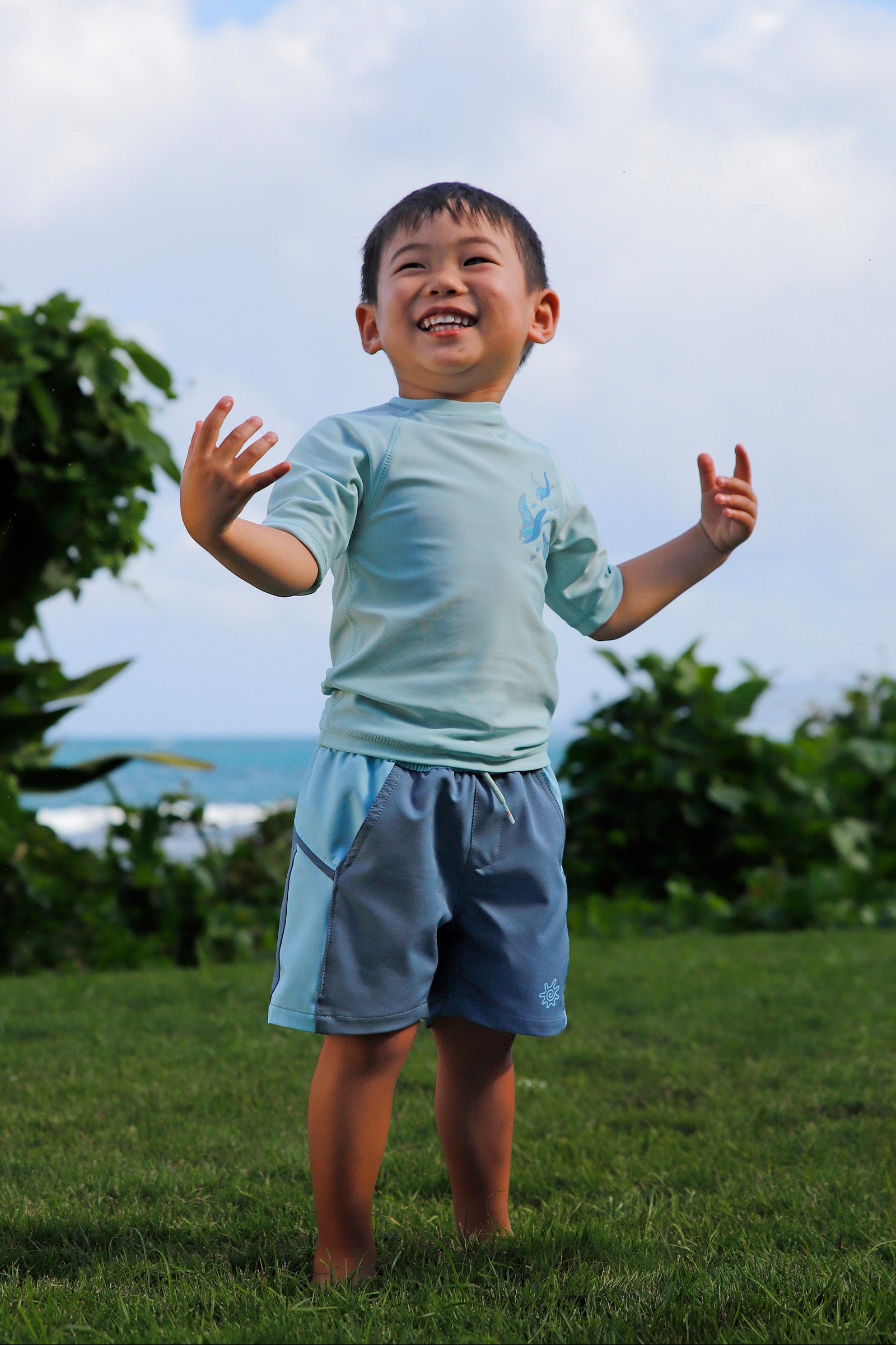 boy in grass in kids crew sunny swim shirt in gliding rays|gliding-rays