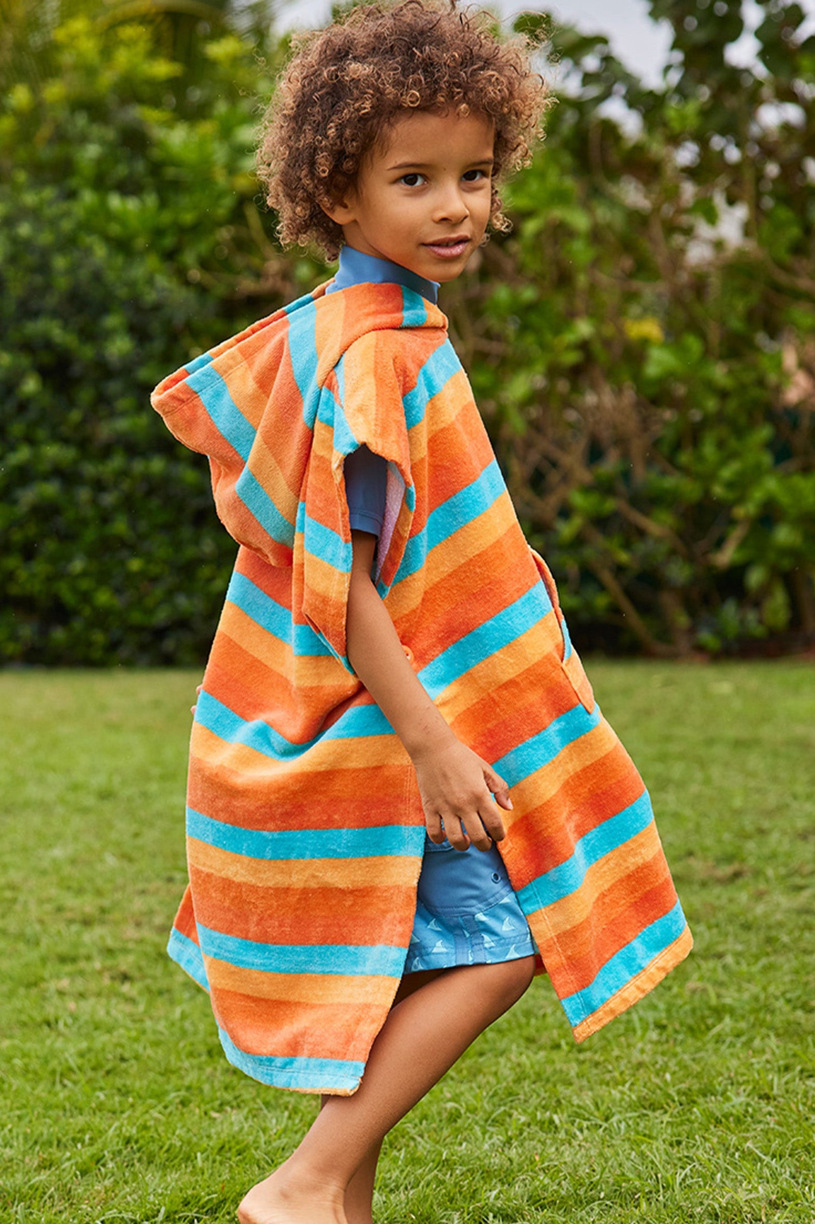 boy in kid's hooded beach poncho in sunset stripe|sunset-stripe