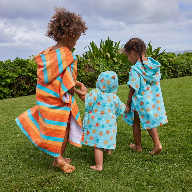 kid's in hooded beach poncho running on grass away|sunny-days