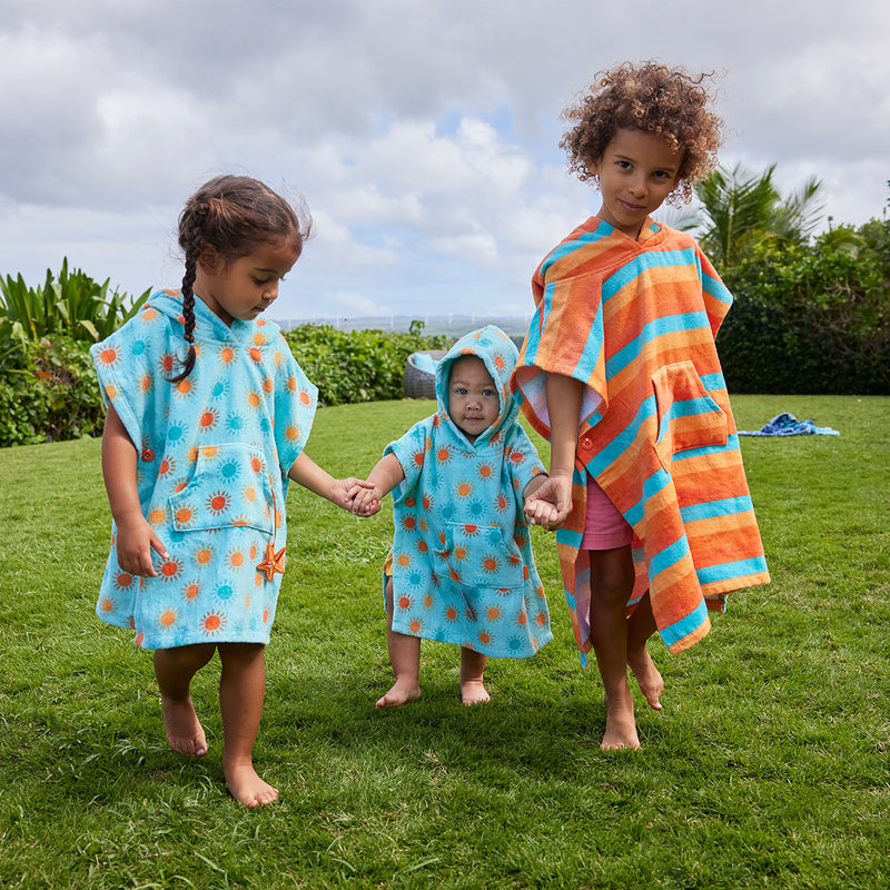 kid's in hooded beach poncho running on grass|sunny-days