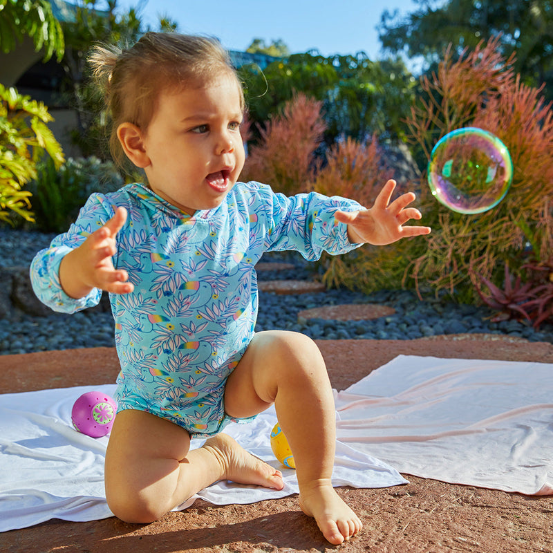 Baby Playing with a Bubble in Baby Girl's Hooded Sunzie in Lively Toucans|lively-toucans