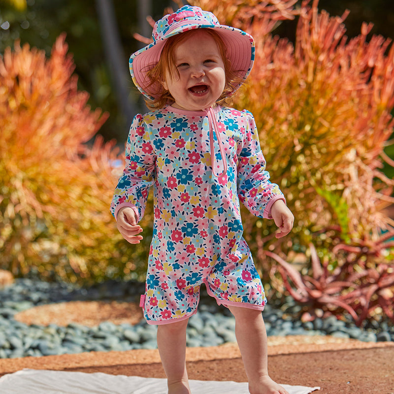 Little baby girl in Baby girl's hoodied sunzie in colorful garden|colorful-garden