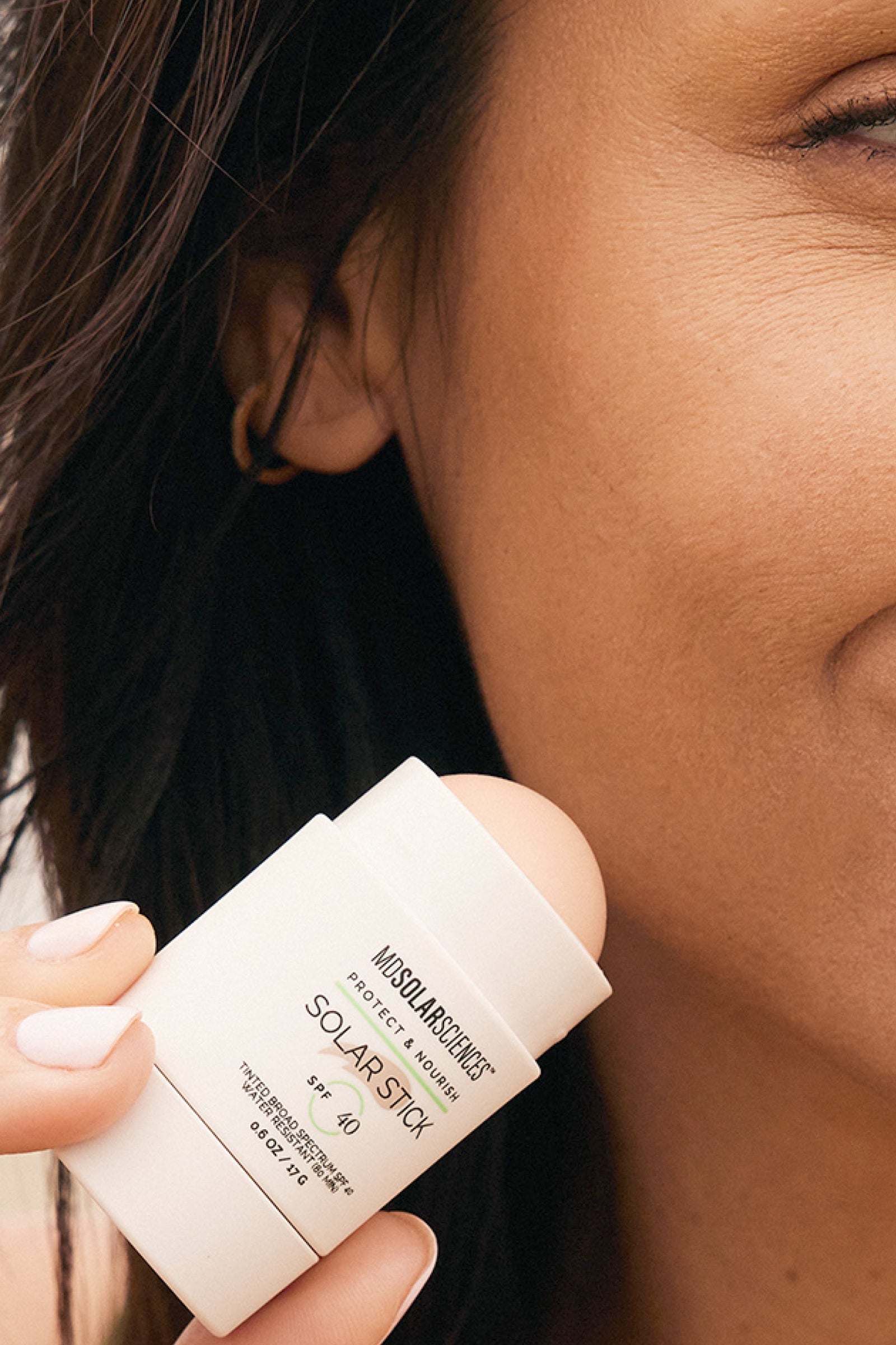 Woman putting on the MDSolarSciences Tinted Solar Stick - Face & Lips Sunscreen - SPF 40+