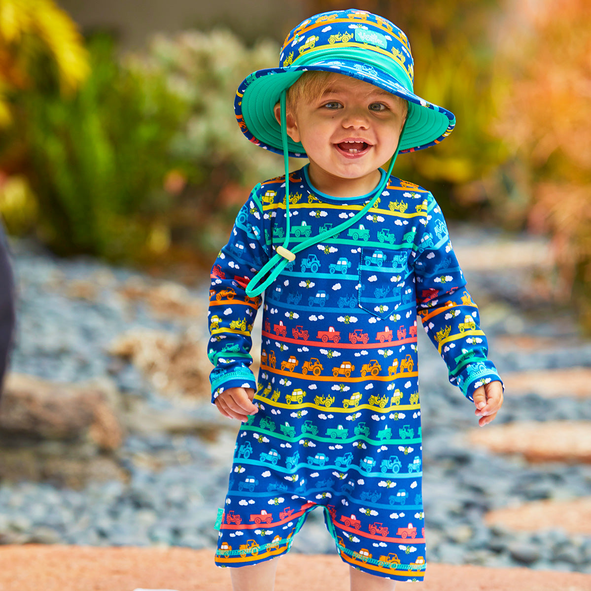 little boy in UV Skinz's baby boy's UV onesie in rainbow tiny trucks|rainbow-tiny-trucks
