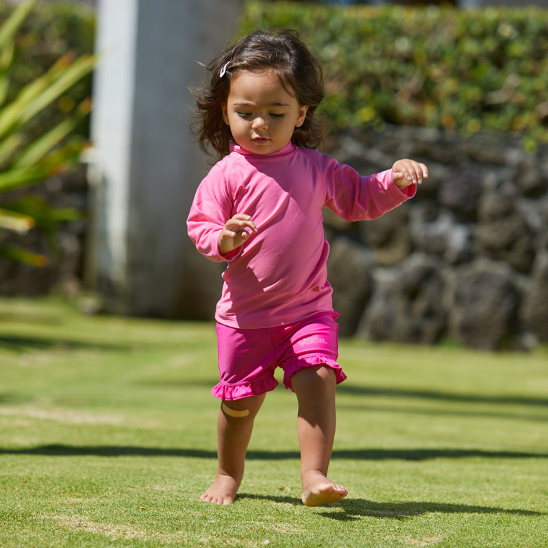 Baby girl playing in UV Skinz's baby long sleeve swim shirt|bubblegum