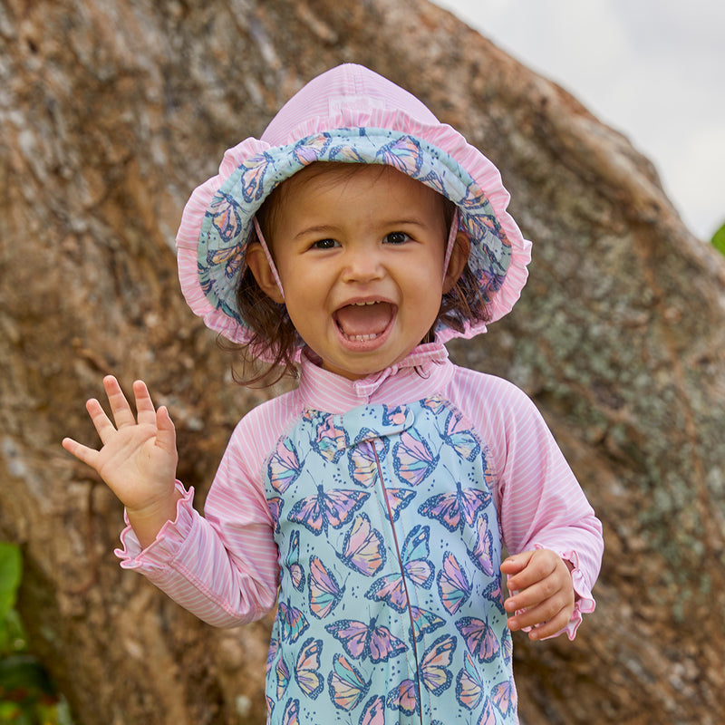 Little girl waving in UV Skinz's baby girl's reversible sun hat|tie-dye-splash