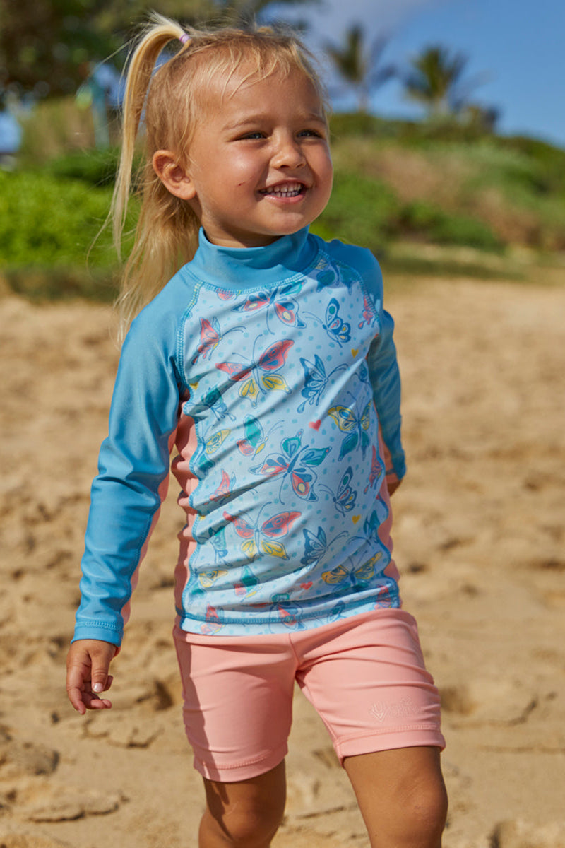 Baby girl on the beach in UV Skinz's girl's swim shorts in apricot|apricot