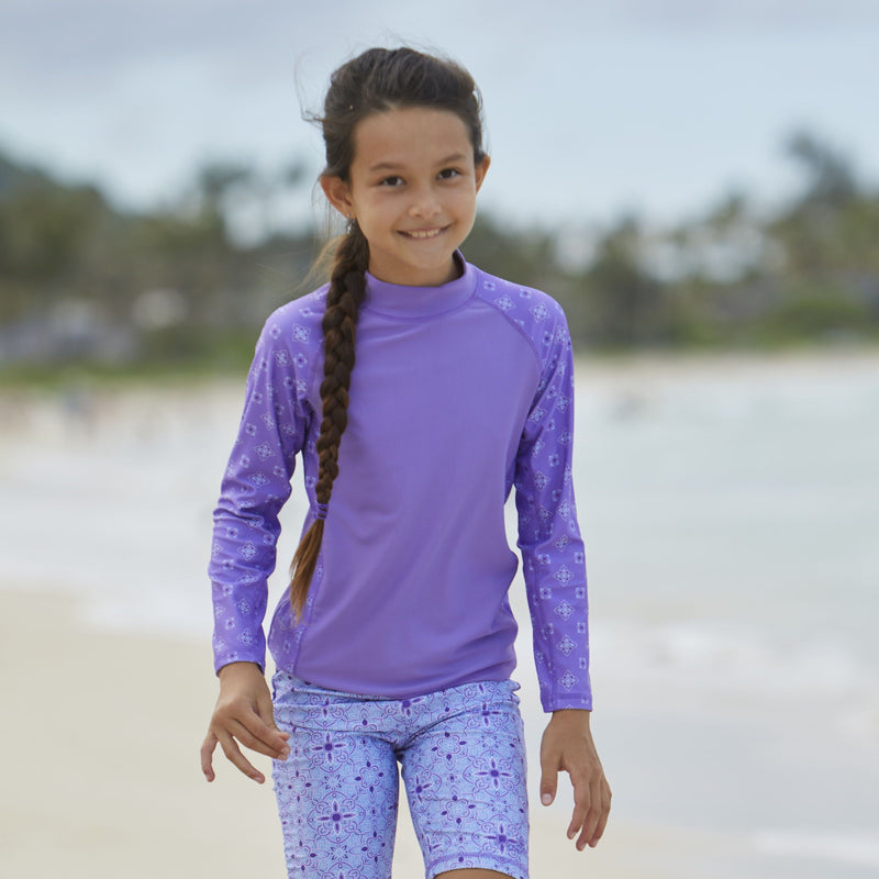Girl wearing UV Skinz's girl's long sleeve UPF swim shirt in purple mini medallion|purple-mini-medallion